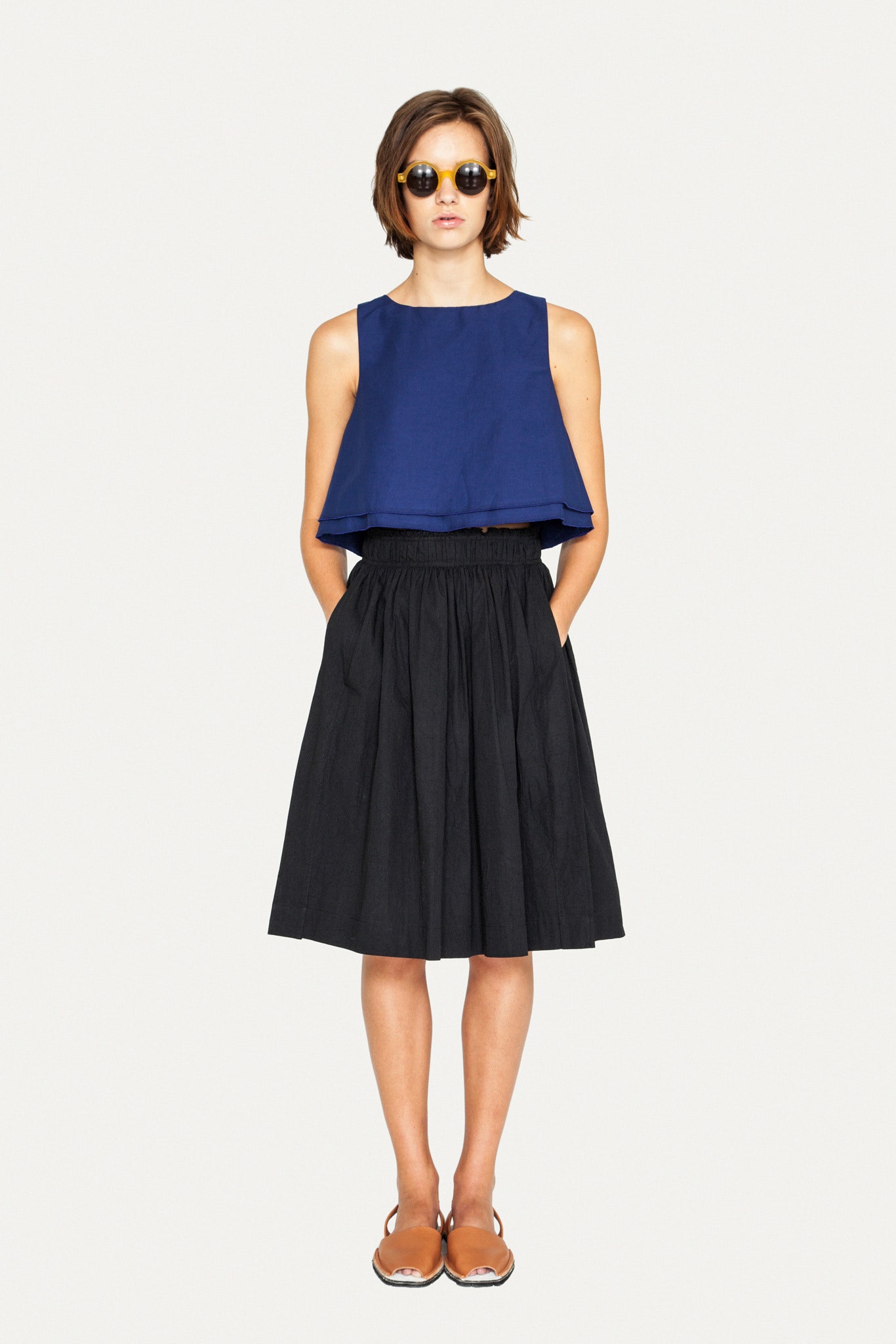 blue cotton sleeveless top and black pleated skirt