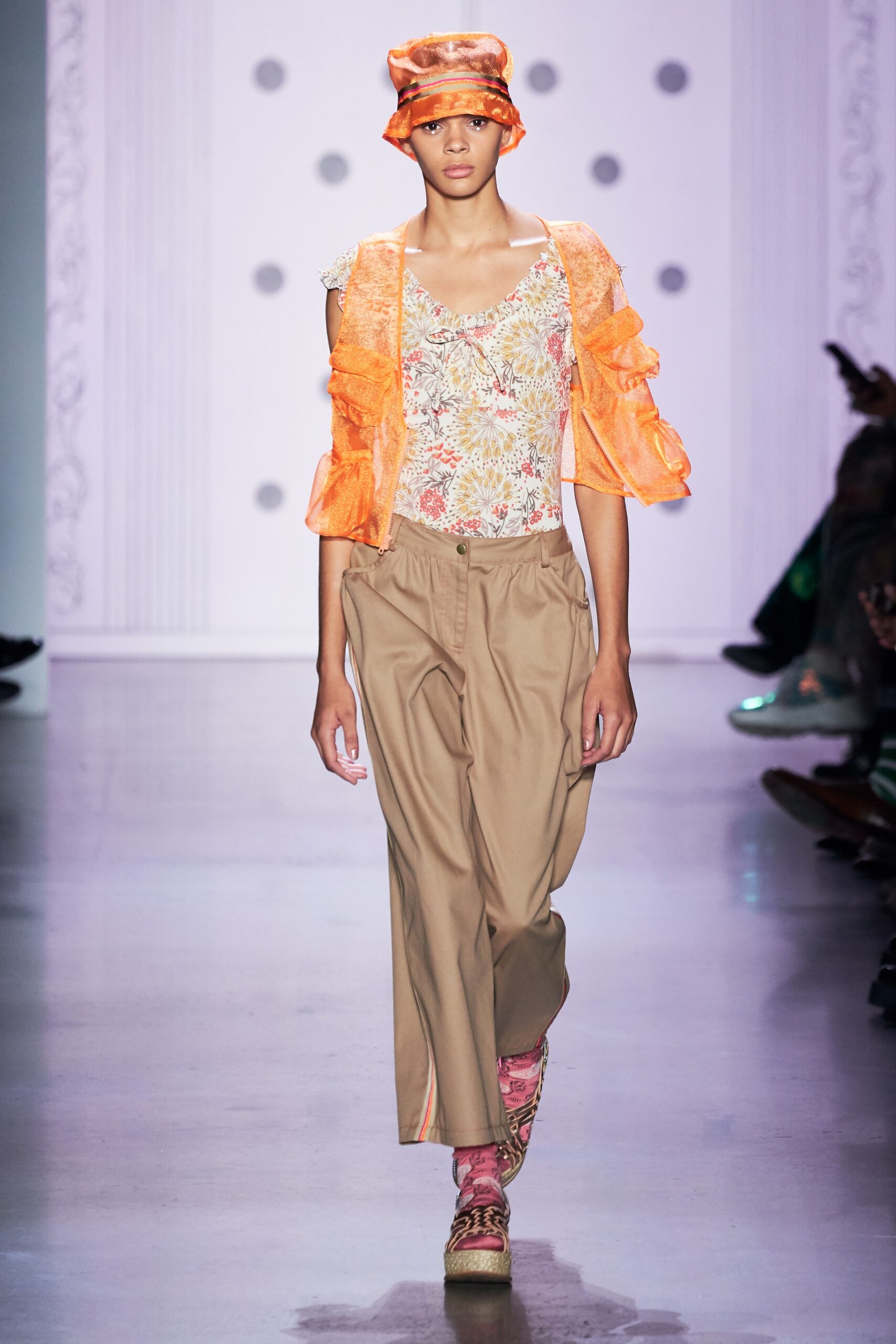 orange ruffled top with beige pants