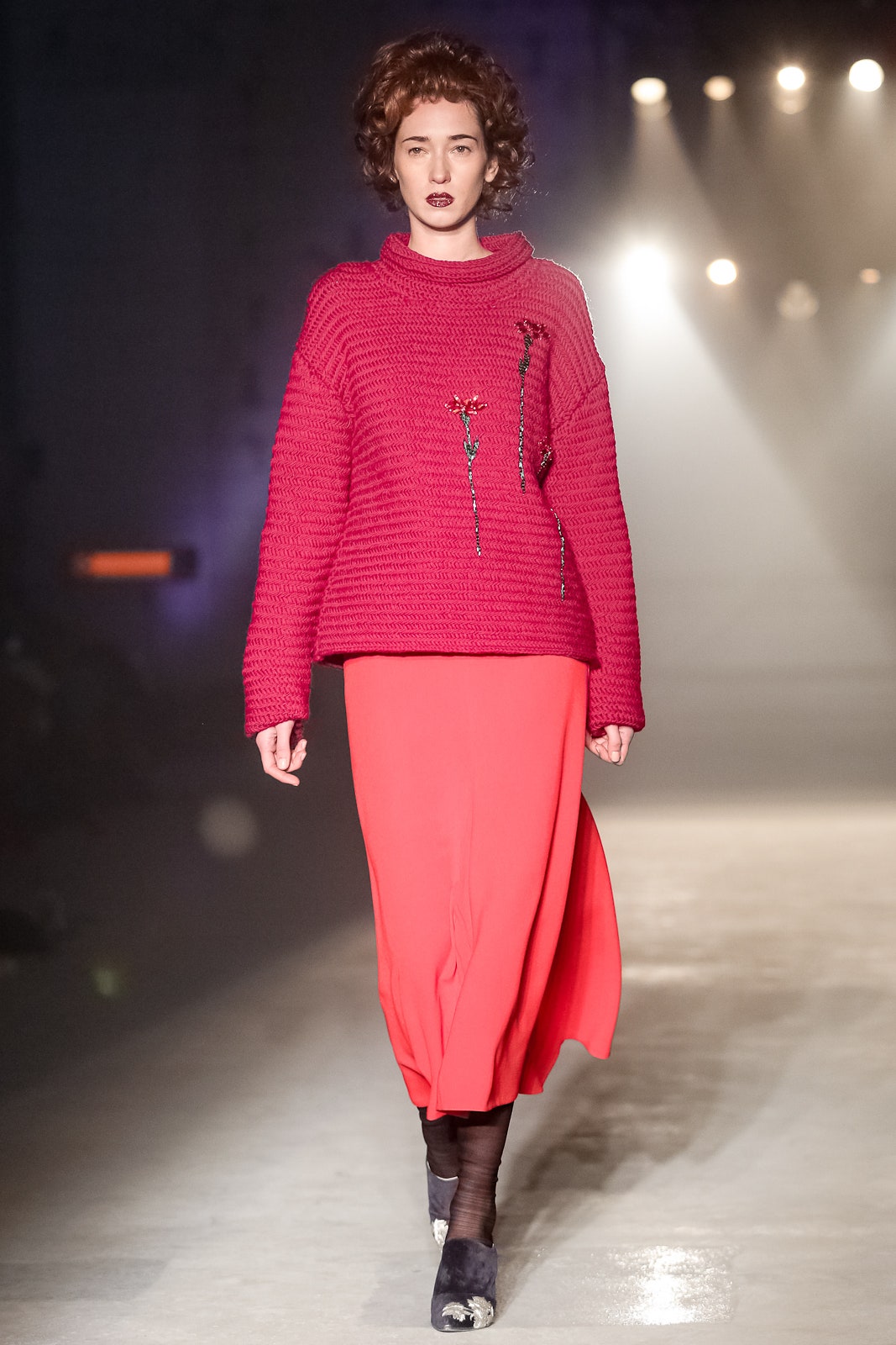 oversized pink sweater with embroidered details and pleated red skirt