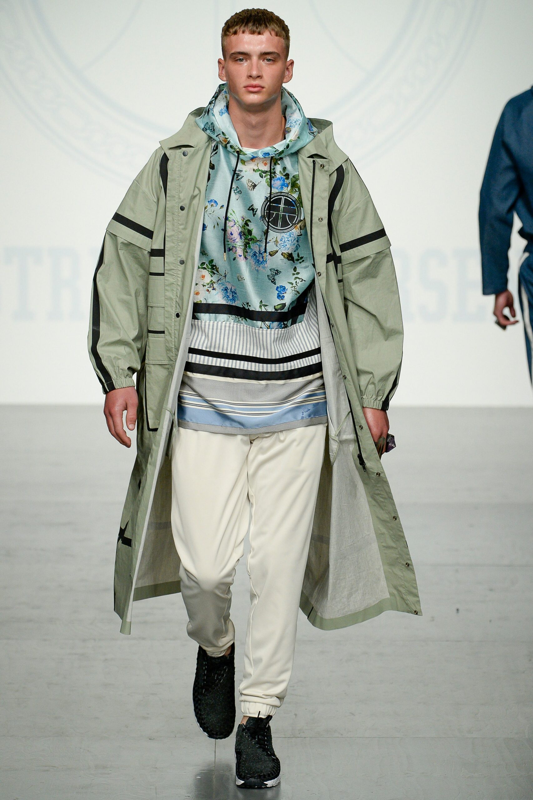 green coat blue hoodie white pants