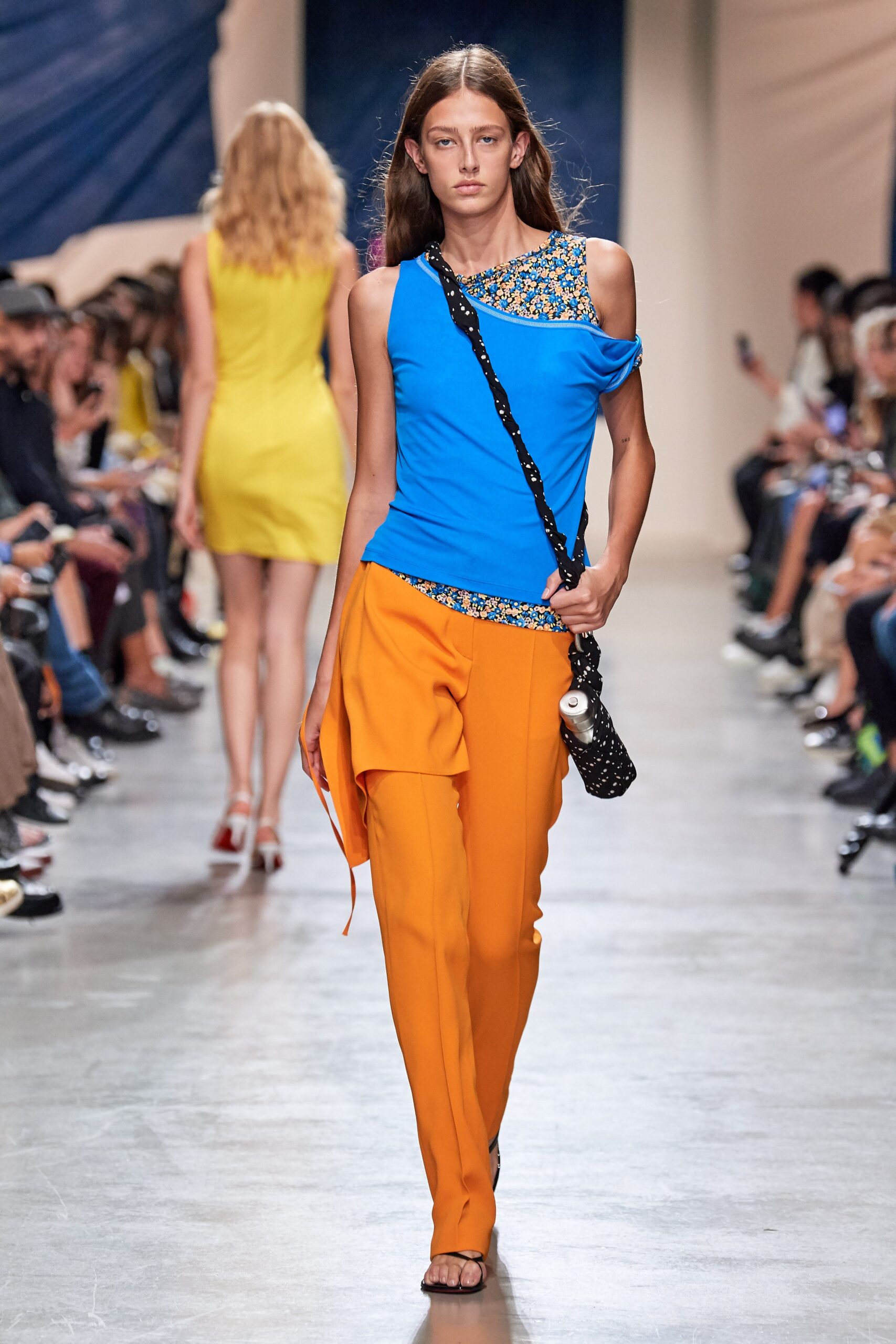 blue asymmetric top with orange pants