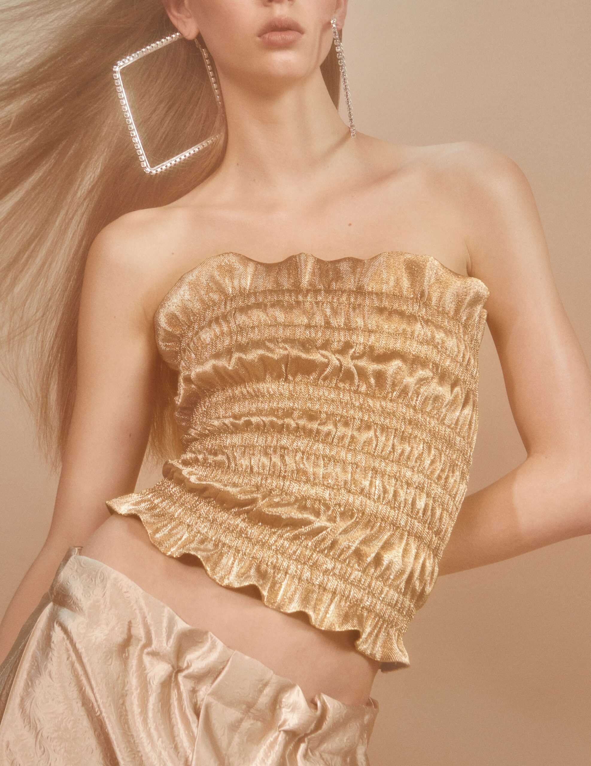 gold strapless top with beige pants