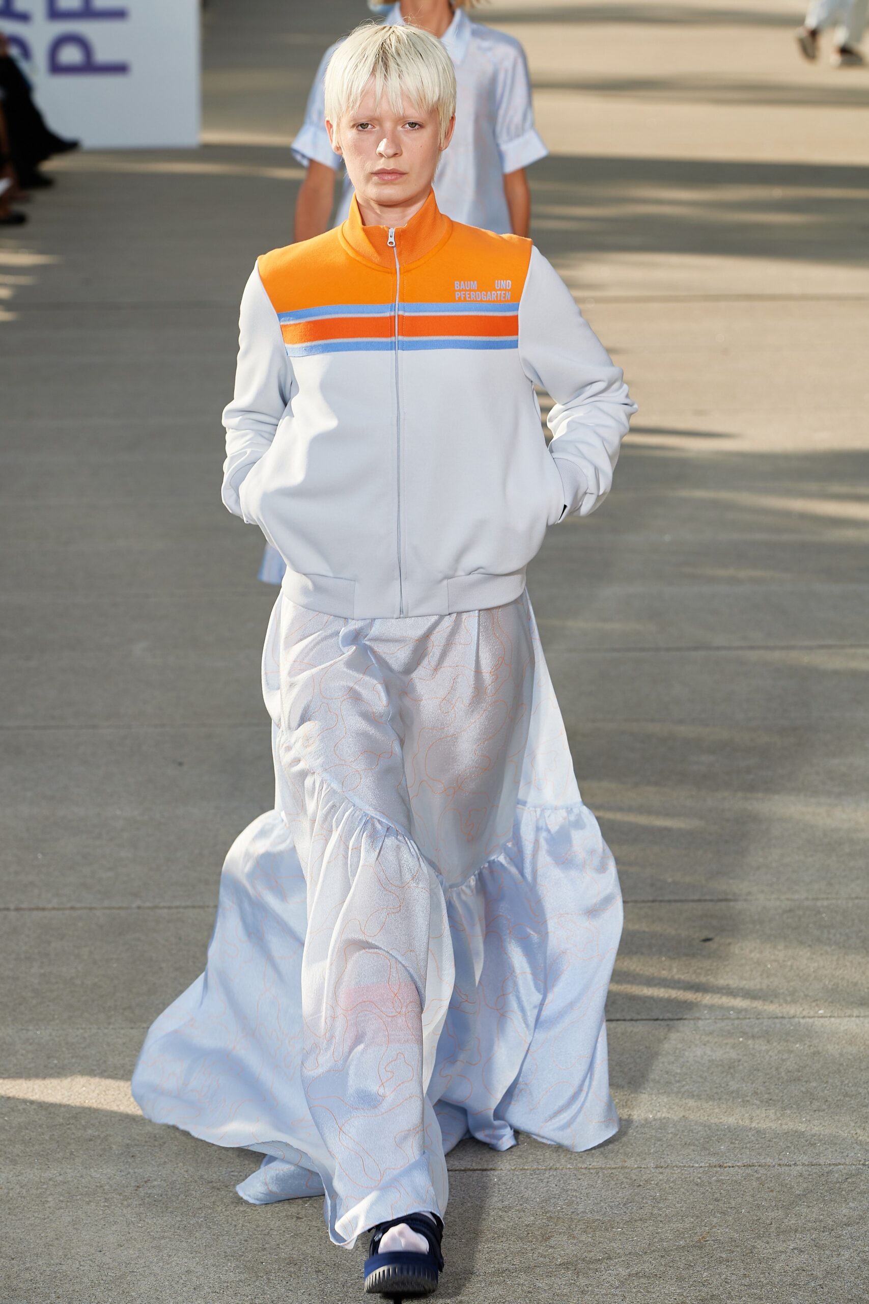 gray jacket with orange accents and flowing blue skirt