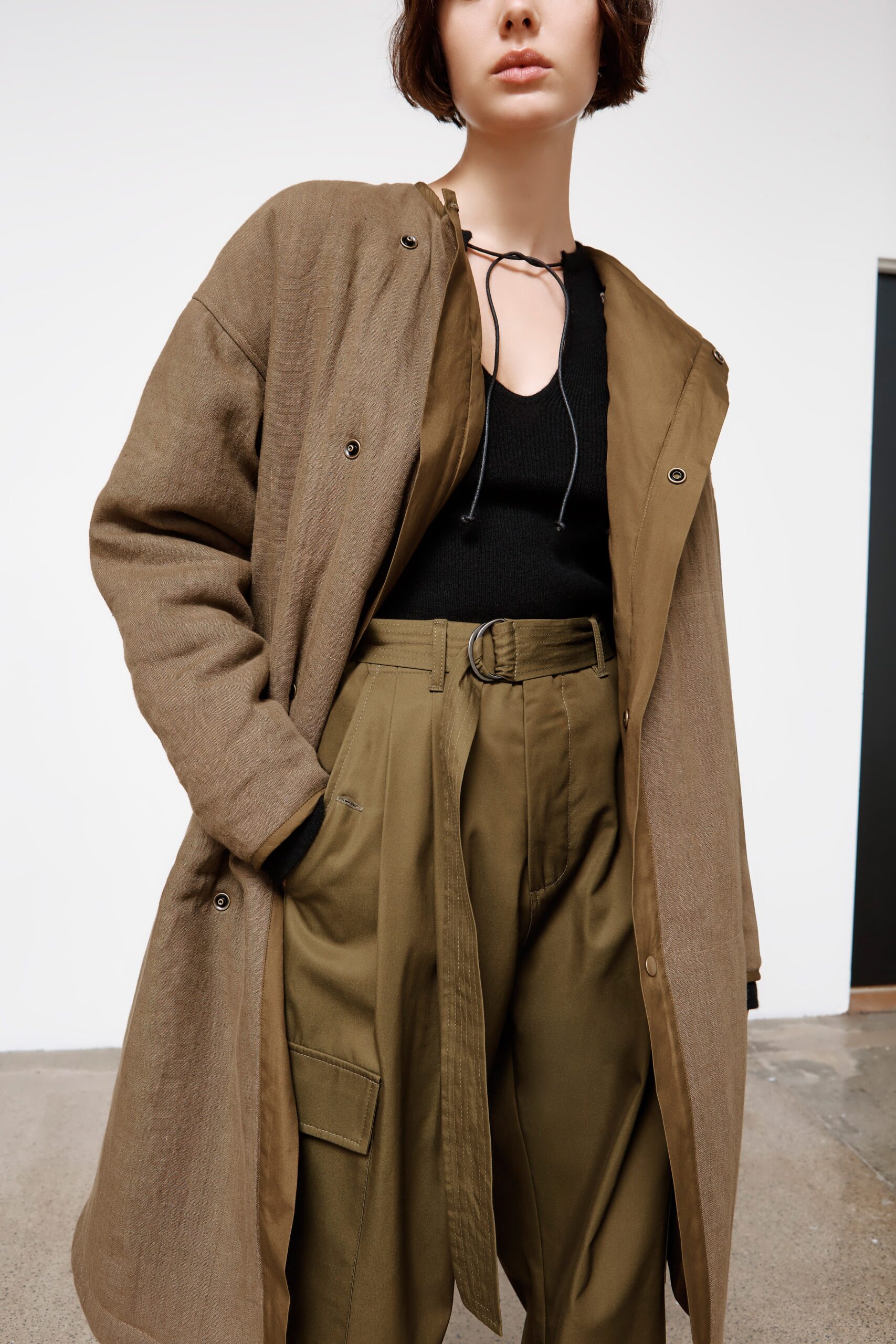 brown coat black top green pants