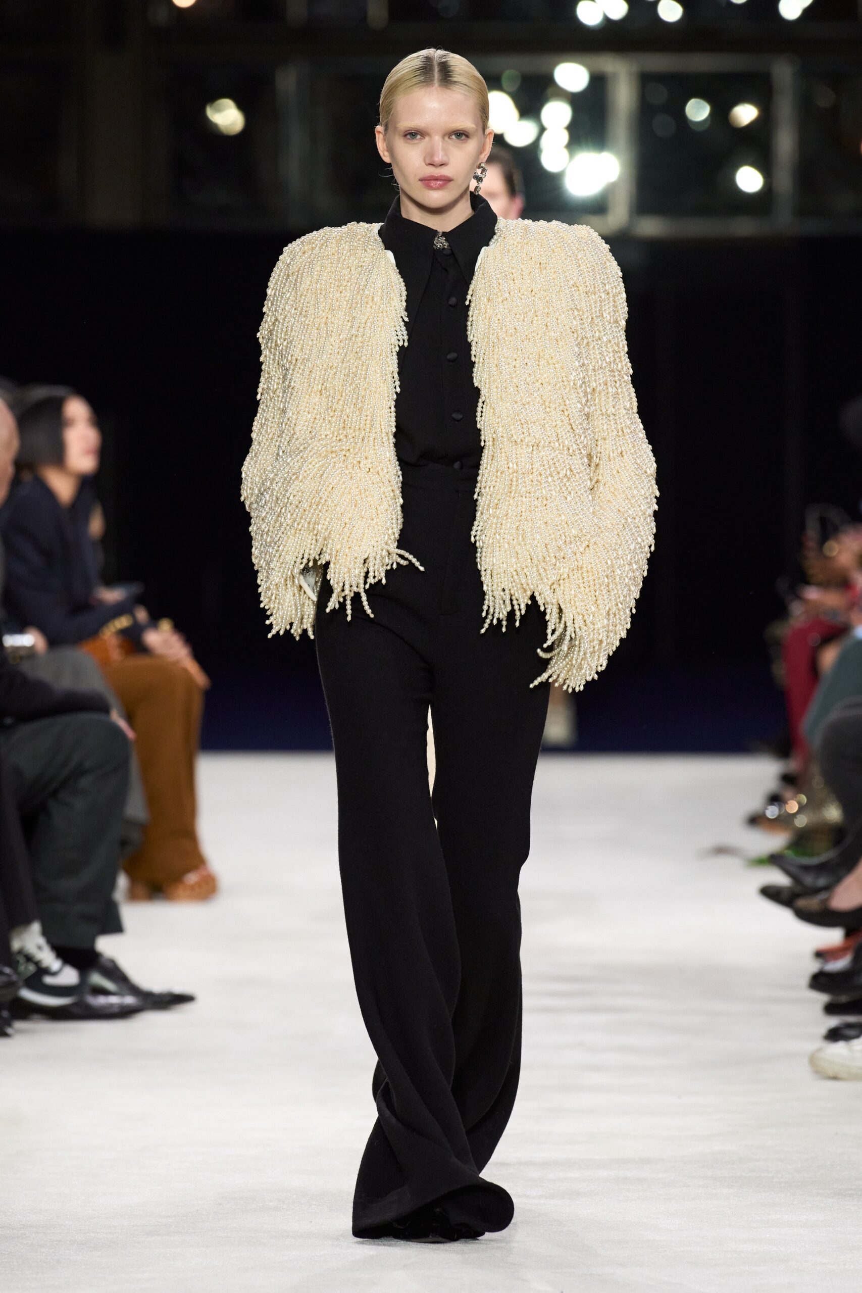 white fringed jacket and black flared pants