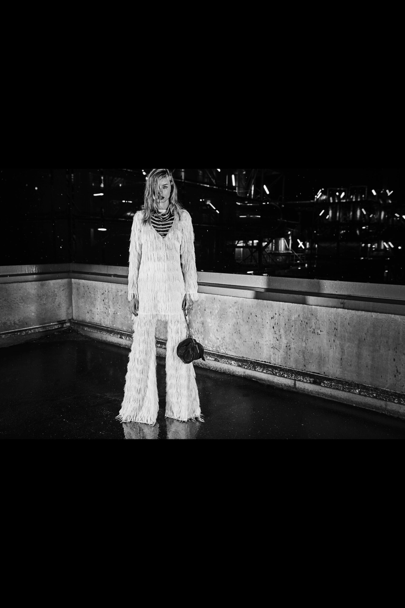 white fringed jumpsuit with black bag
