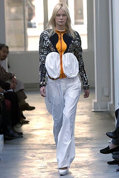 black and orange fitted top with white pants