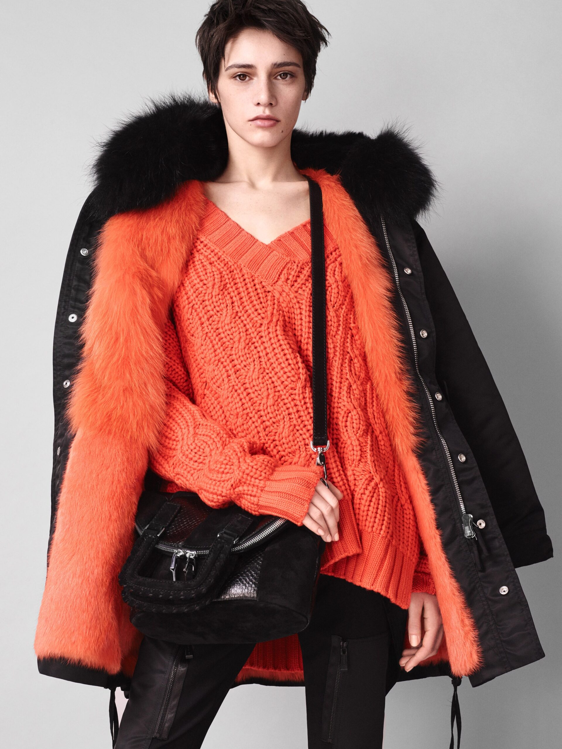 black faux-fur coat and orange sweater