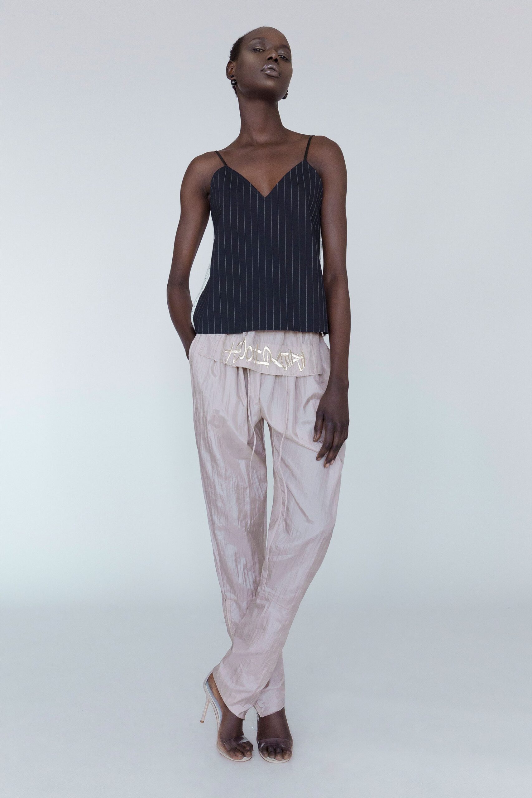 black silk sleeveless top and beige pants