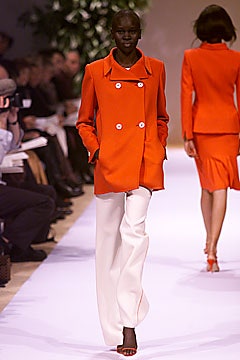 orange fitted coat with white pants