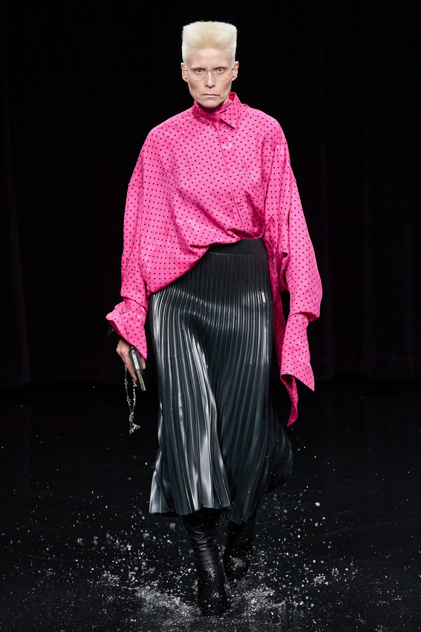 pink polka-dot oversized shirt and black pleated skirt