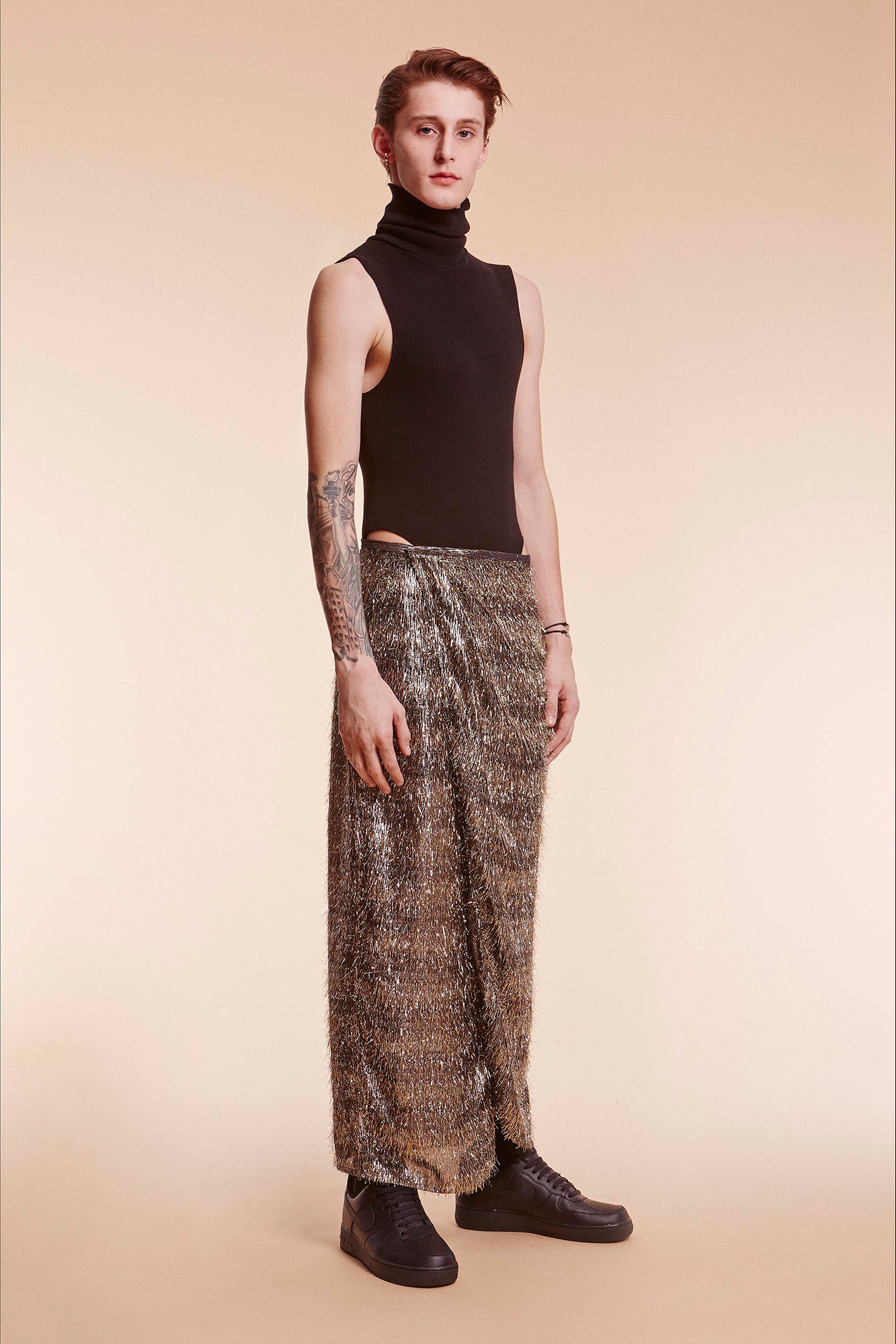 black bodysuit and gold pleated skirt