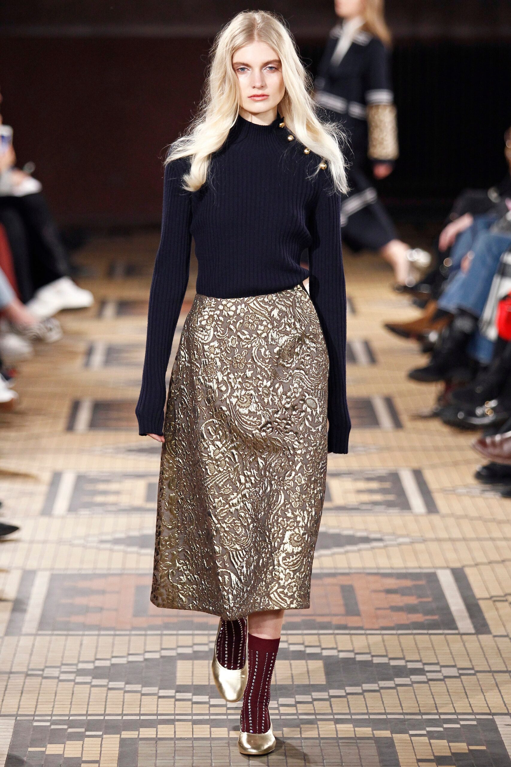 navy fitted turtleneck top and gold pleated skirt