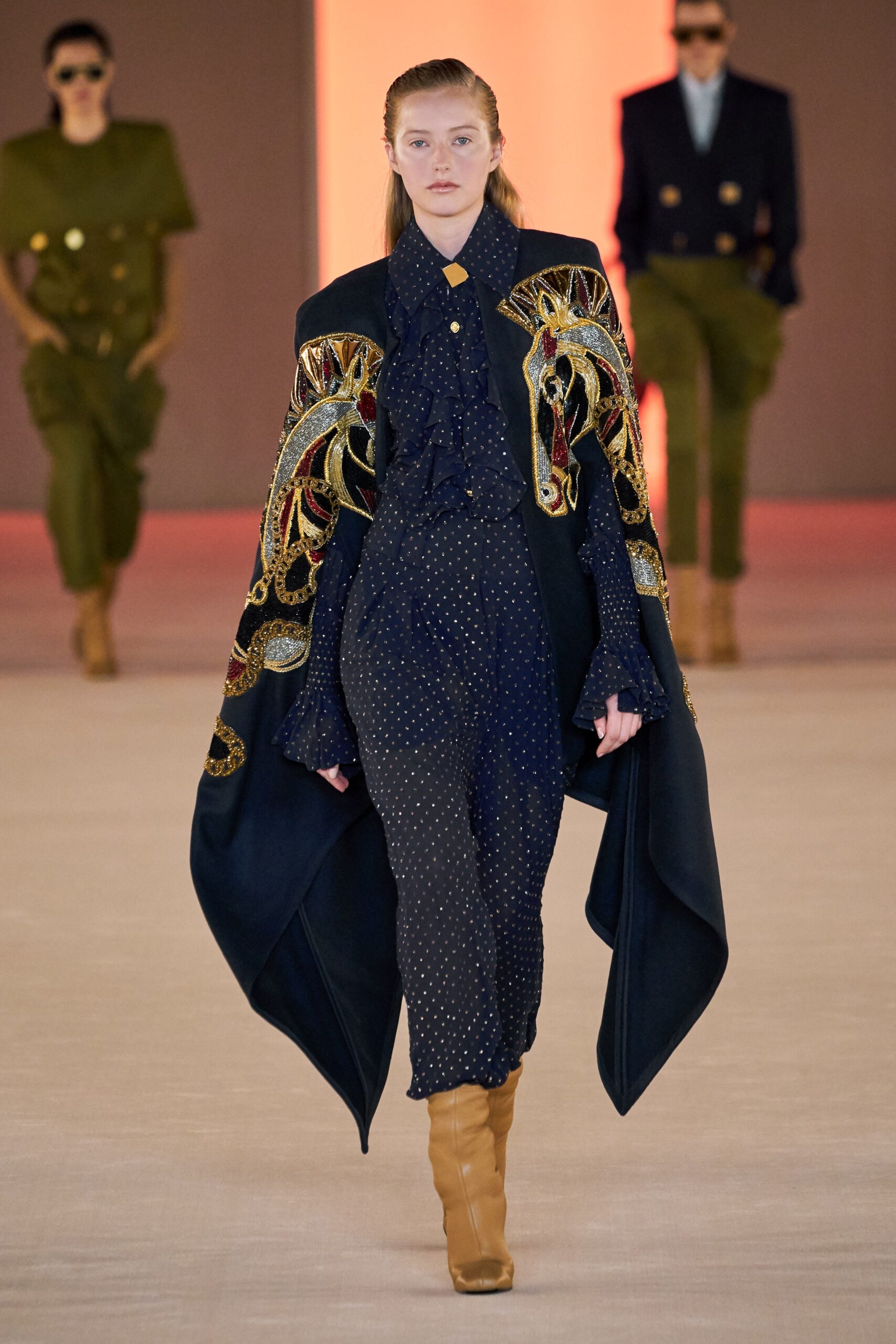 black embroidered cape and blue jumpsuit