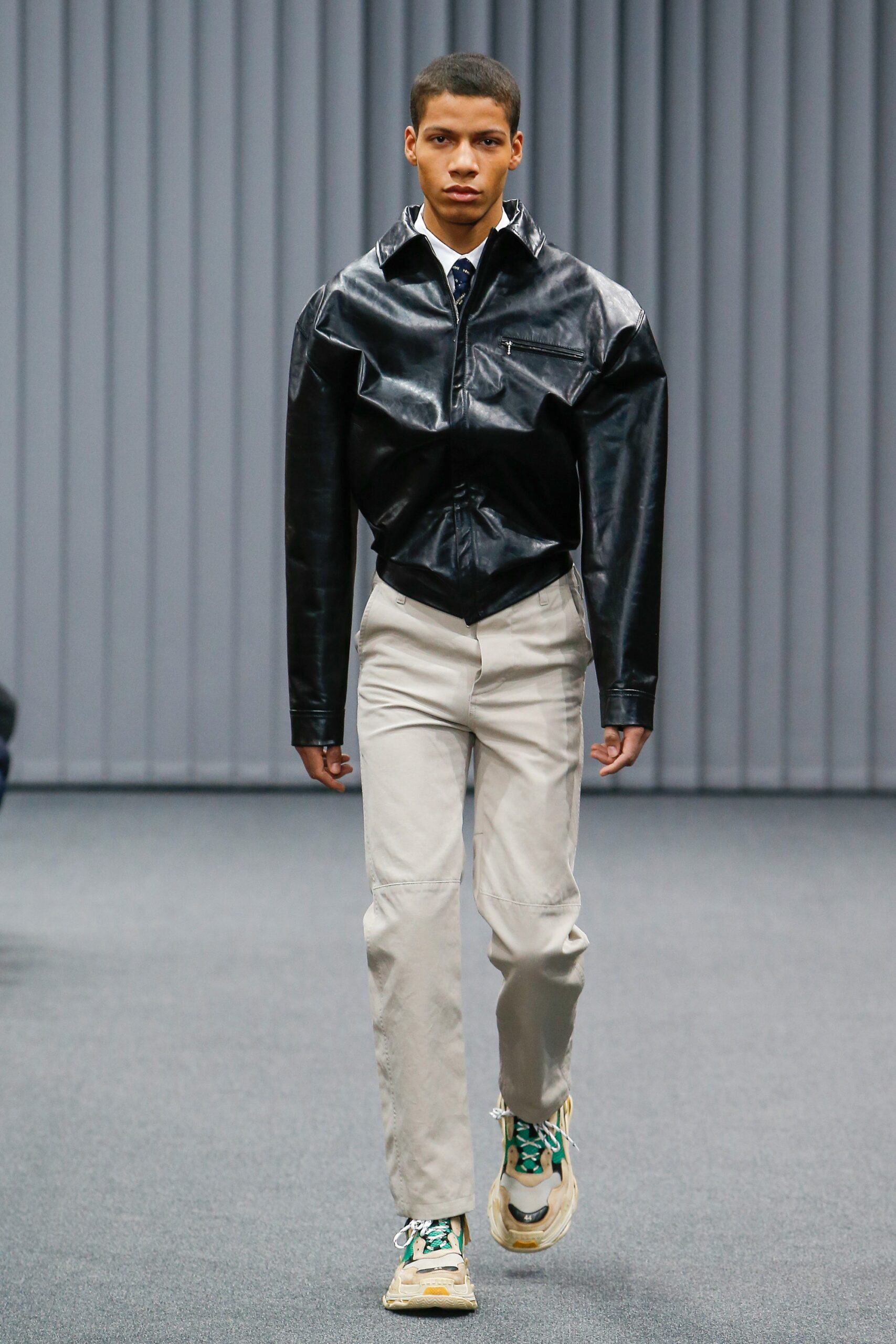 black leather fitted jacket and beige pants