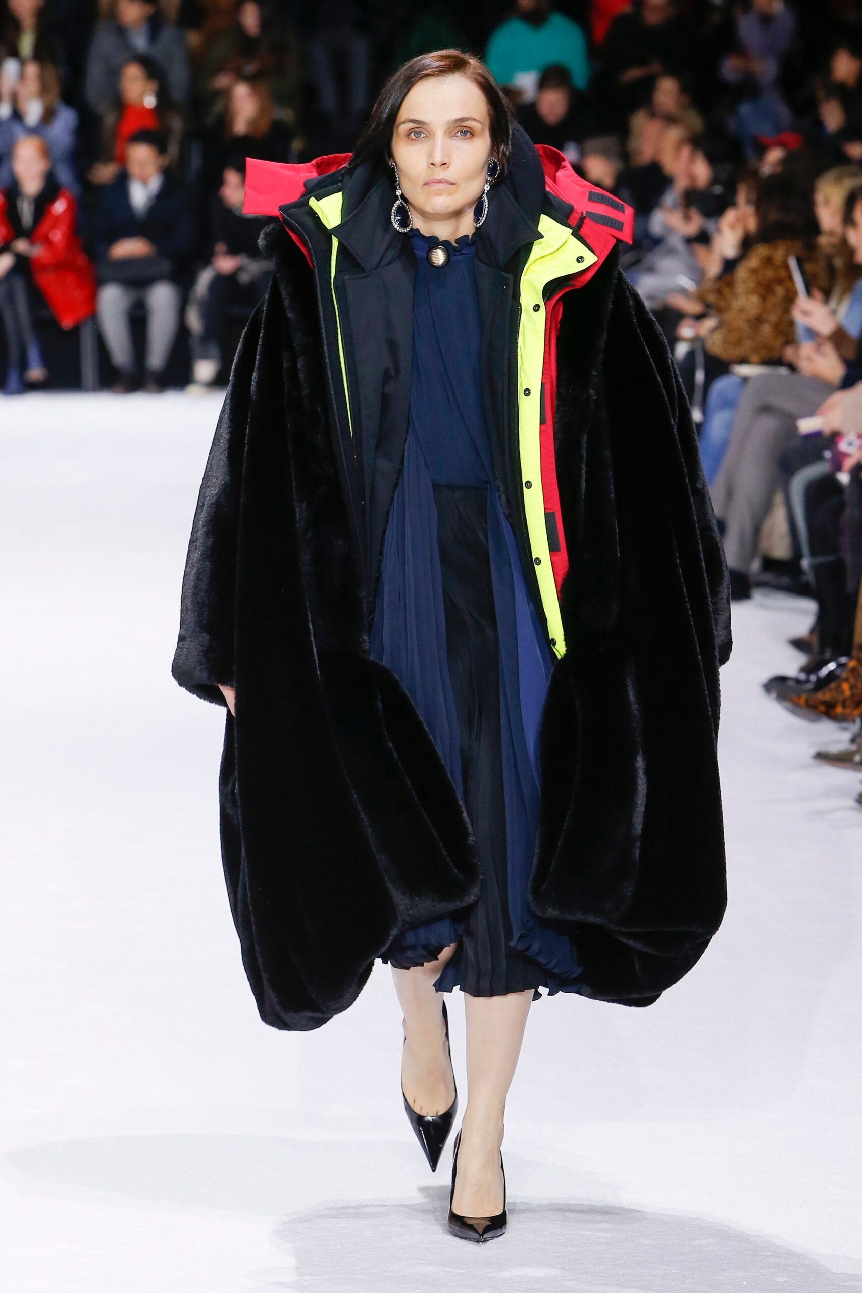 black oversized faux-fur coat and navy pleated dress