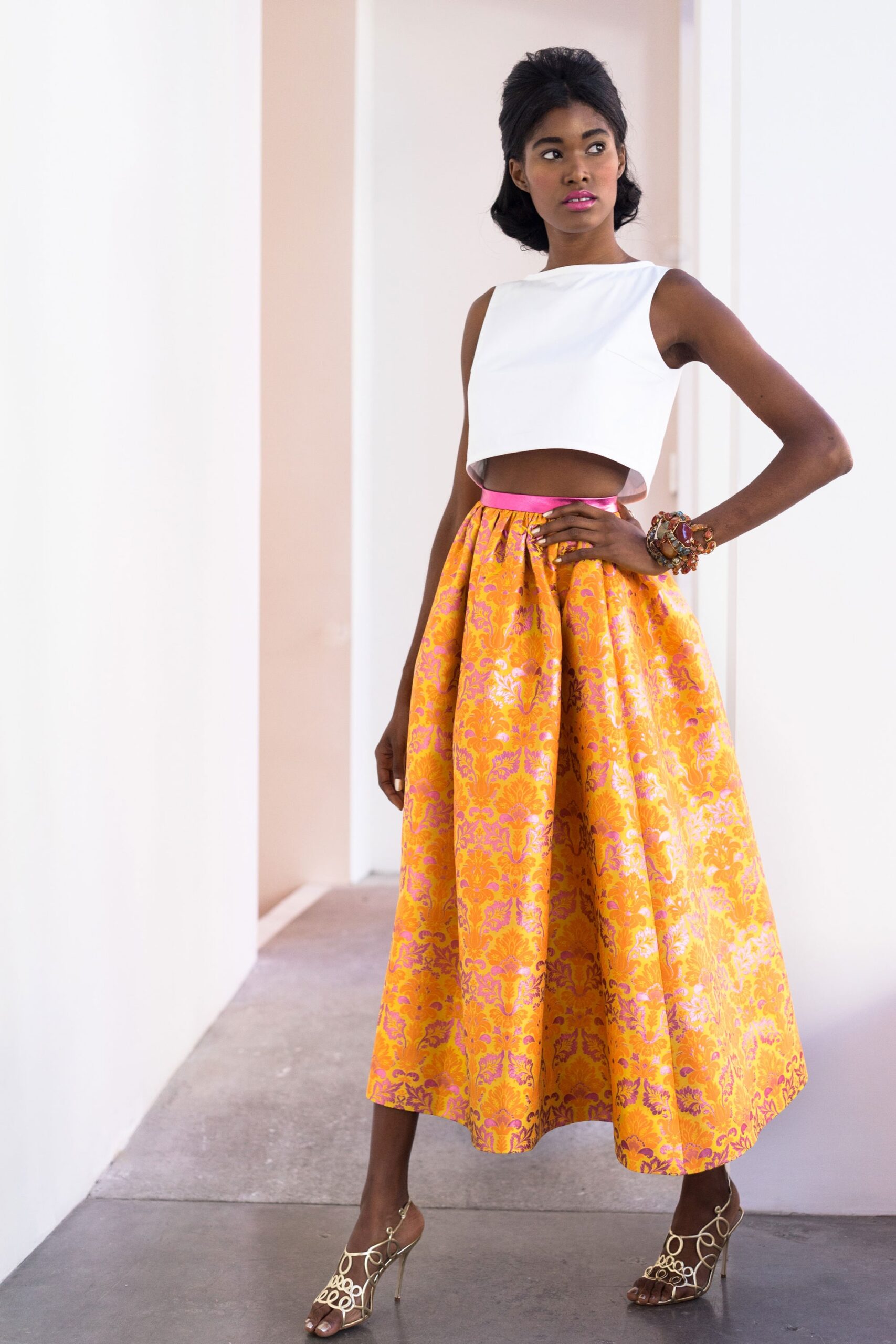 white fitted top and orange pleated skirt