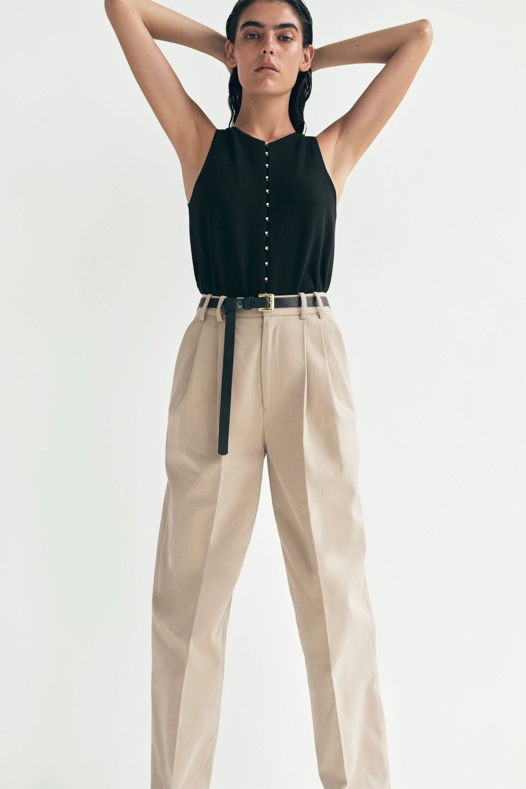 black fitted sleeveless top with beige pants