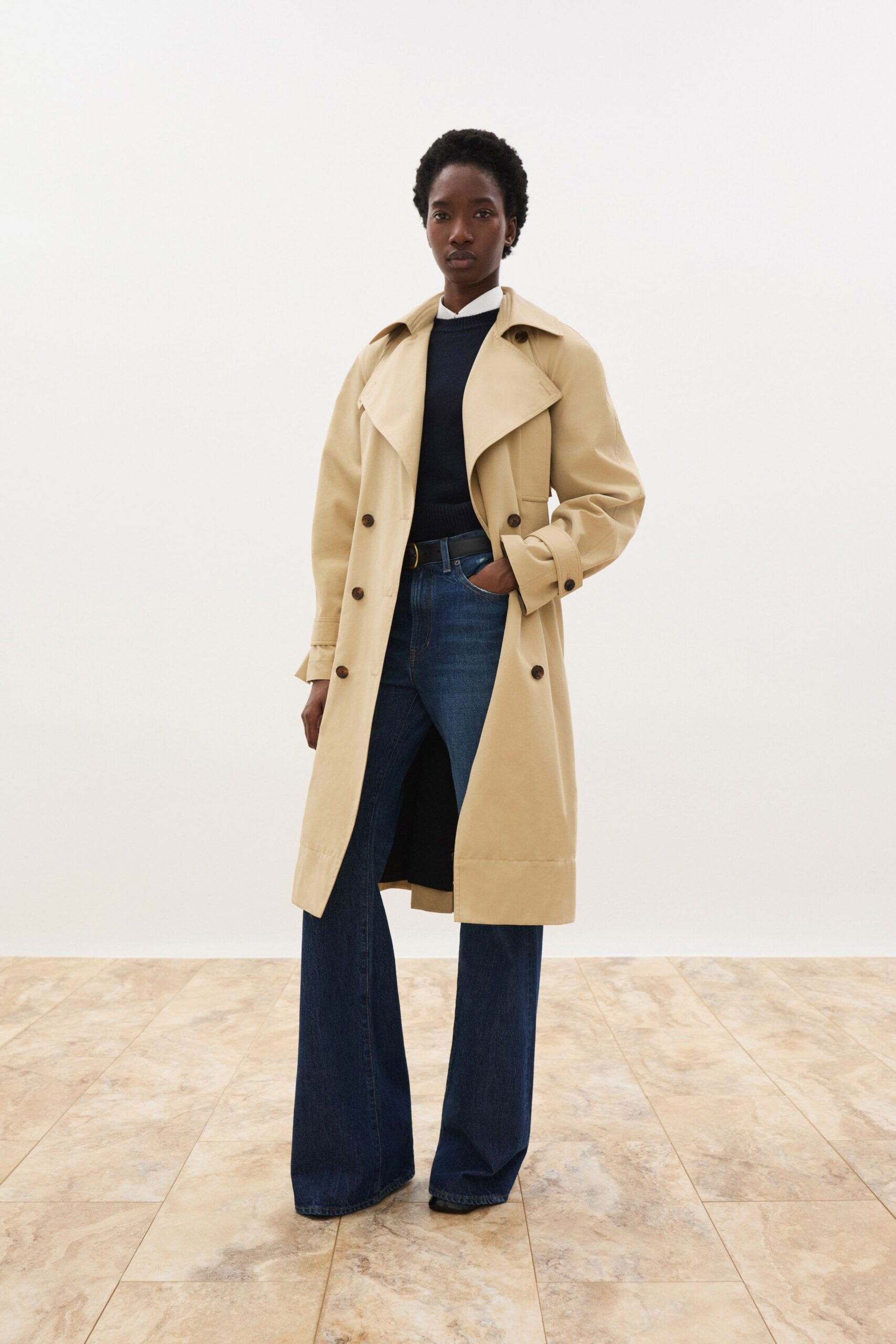 beige trench coat with black top and blue jeans