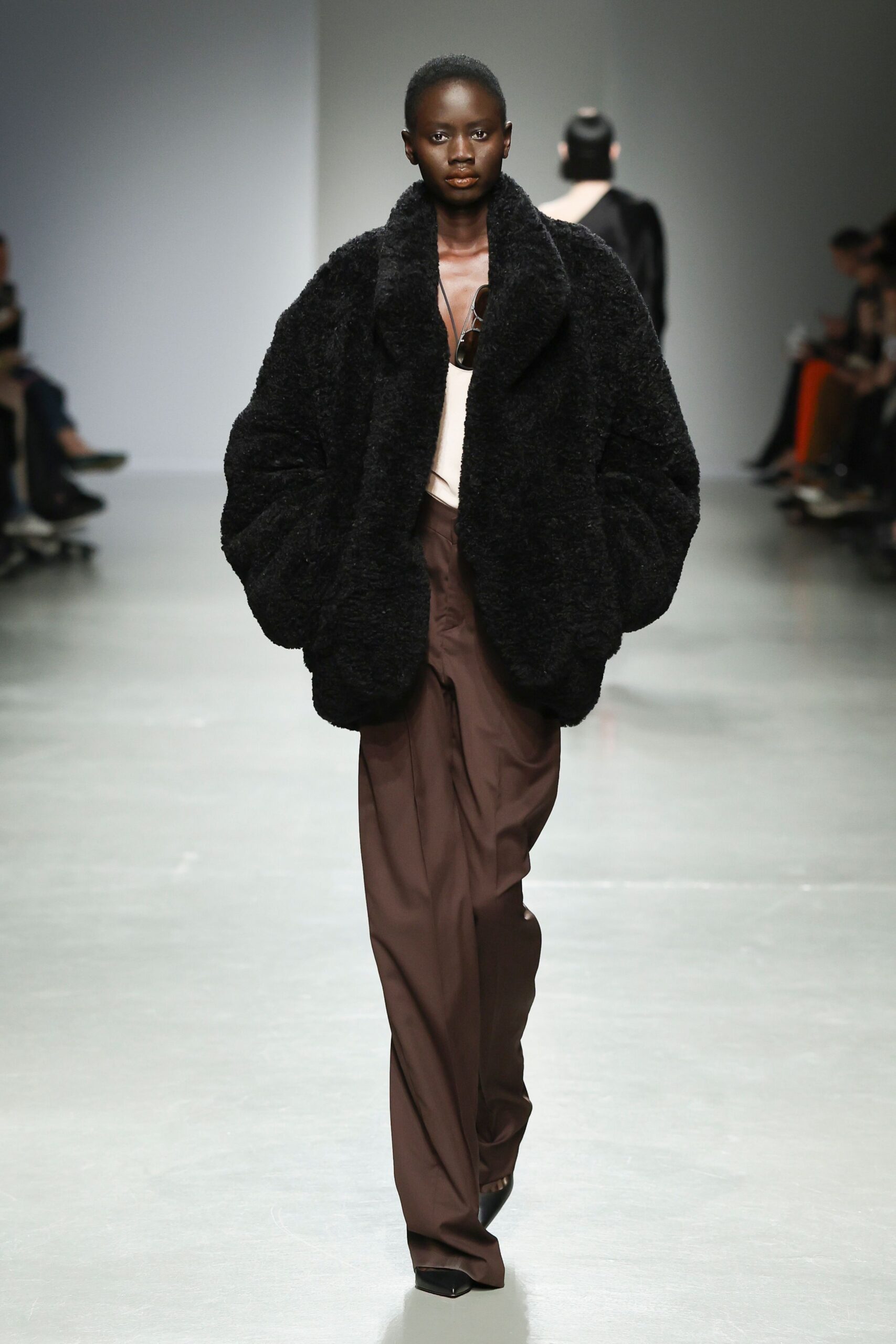 black faux-fur oversized coat and brown relaxed pants