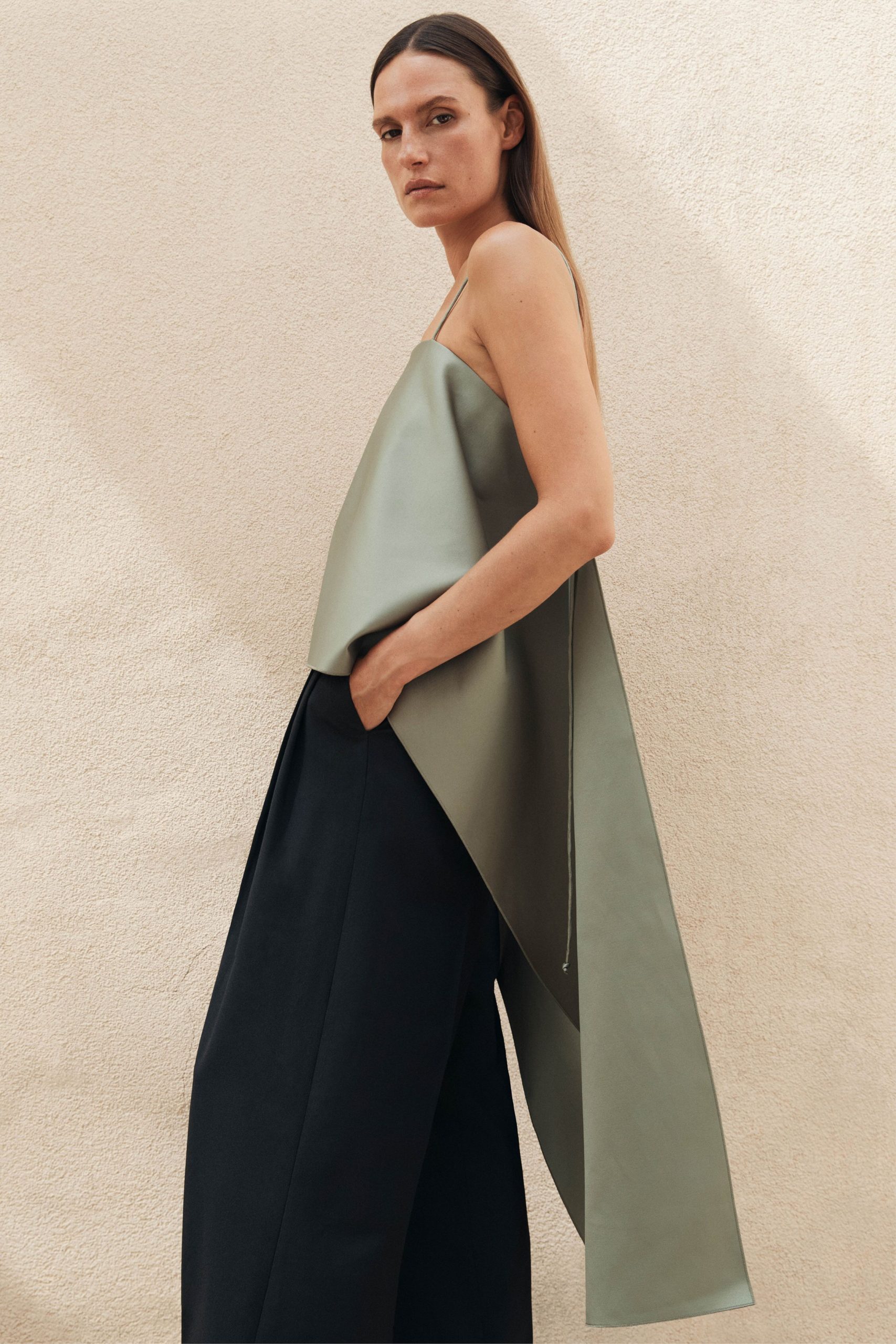 green silk draped top and black tailored pants