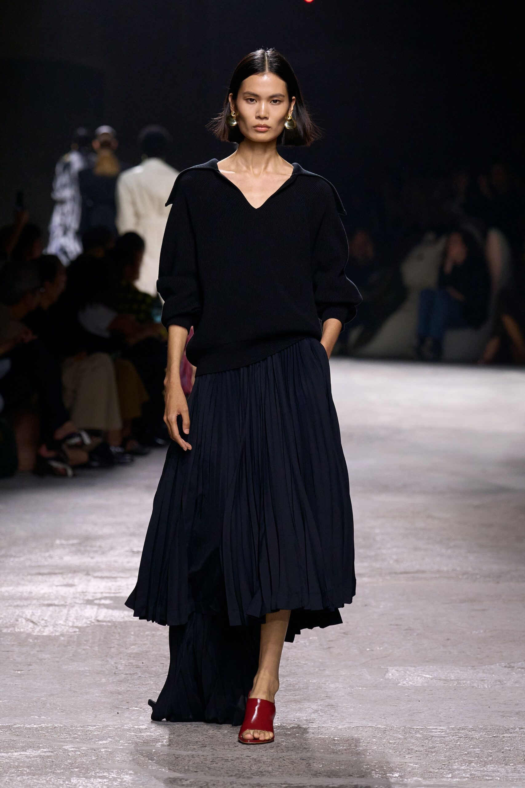 black sweater and navy pleated skirt