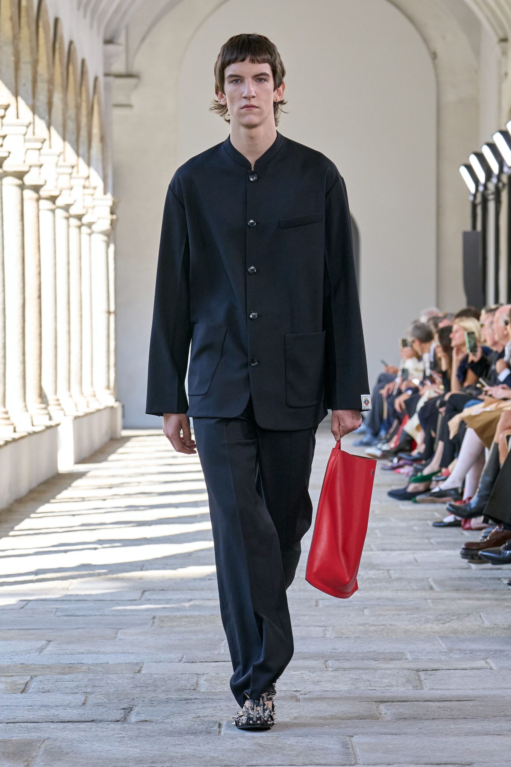 black tailored suit with red bag
