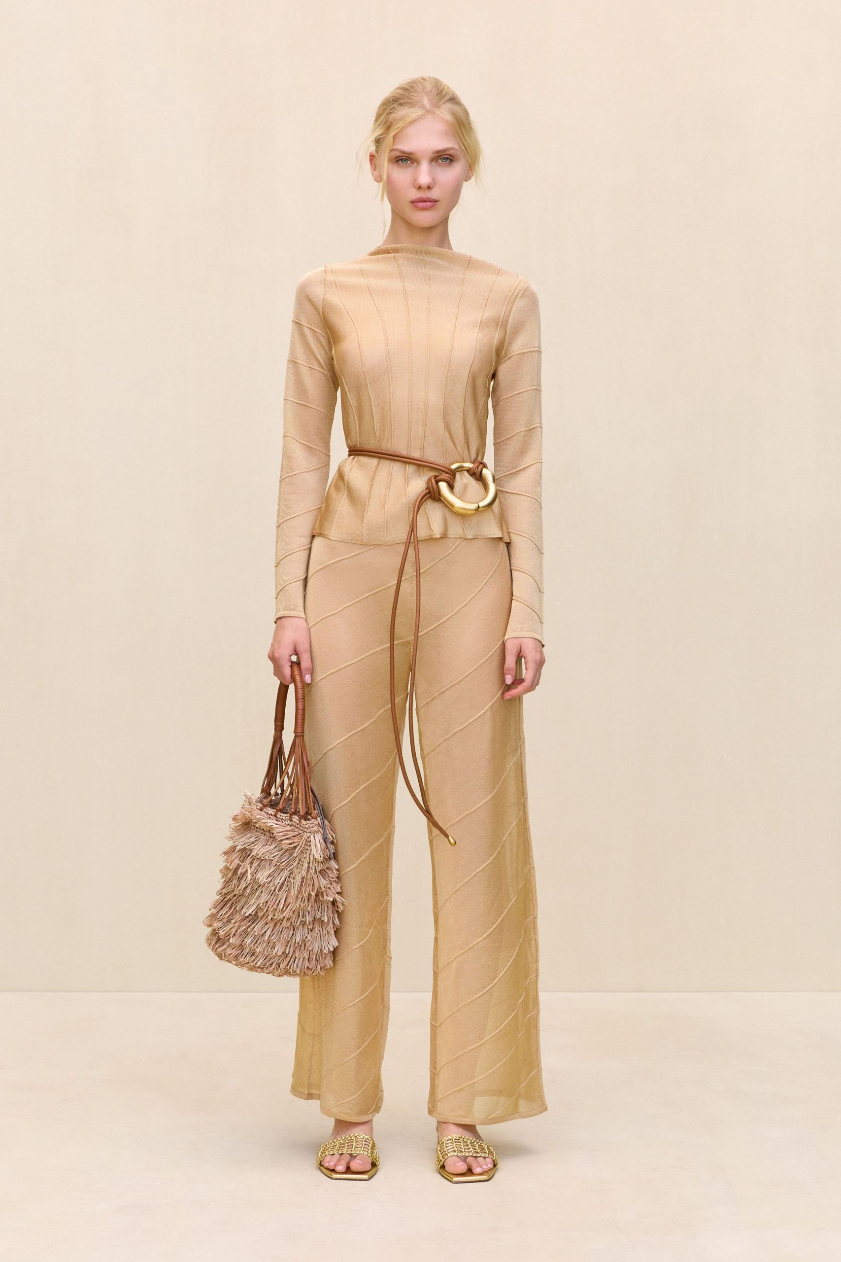 beige fitted jumpsuit with fringed bag