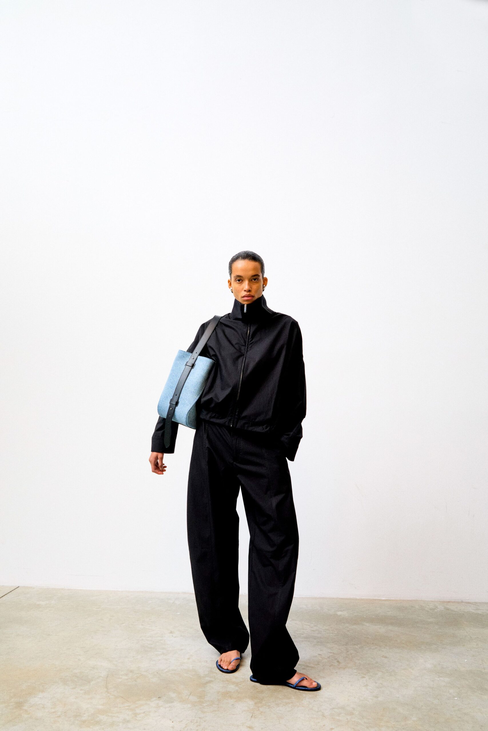 black relaxed jumpsuit with blue bag