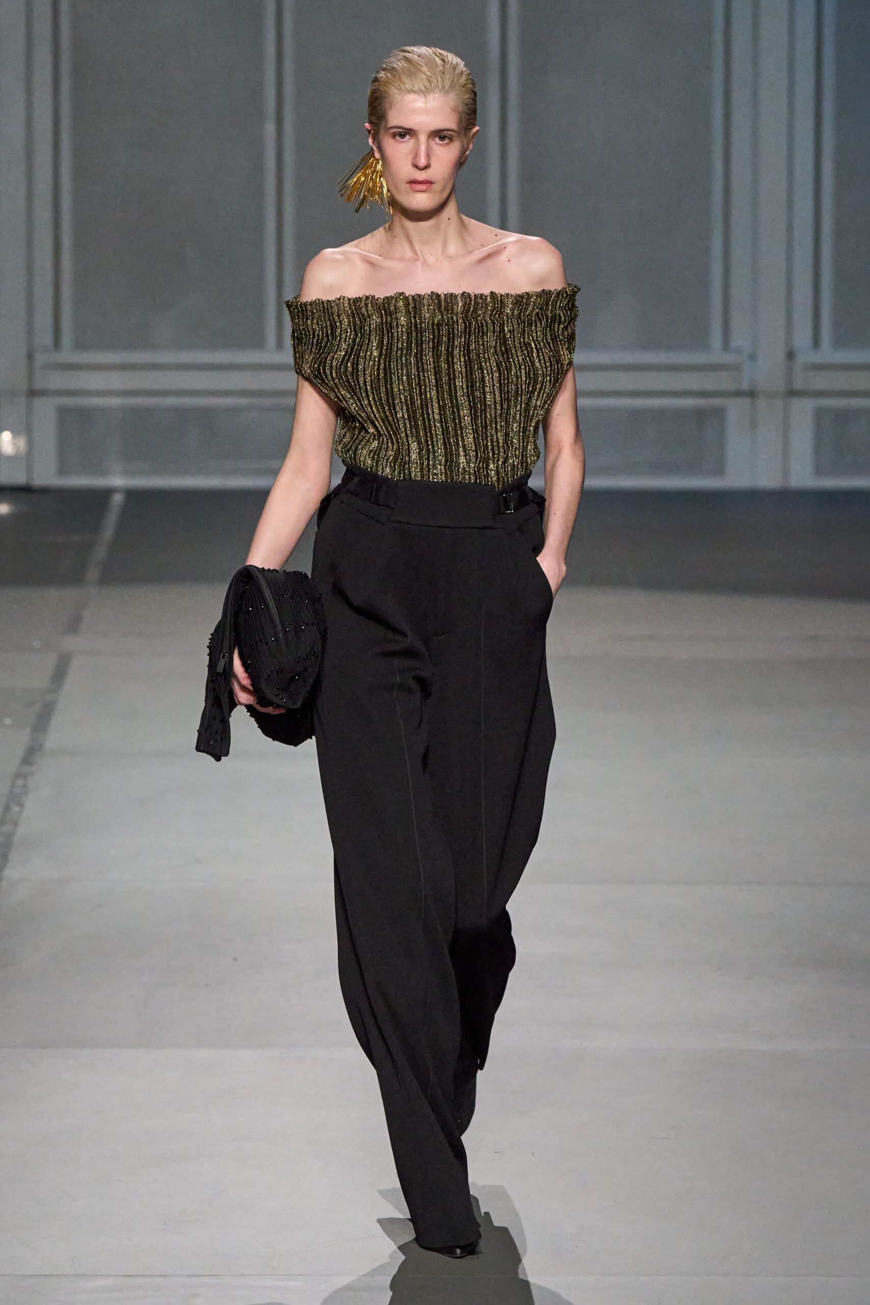 gold pleated off-shoulder top with black pants