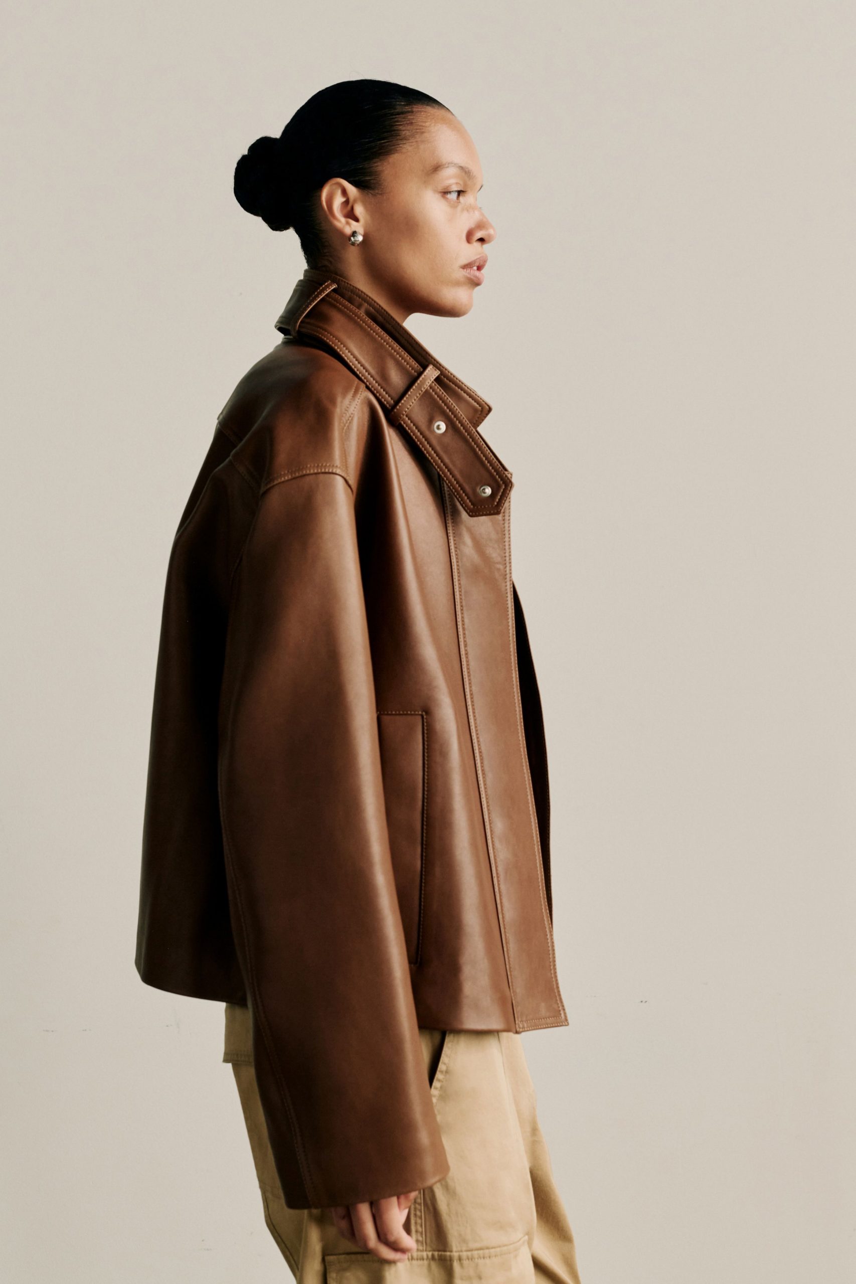 brown leather oversized jacket and beige pants