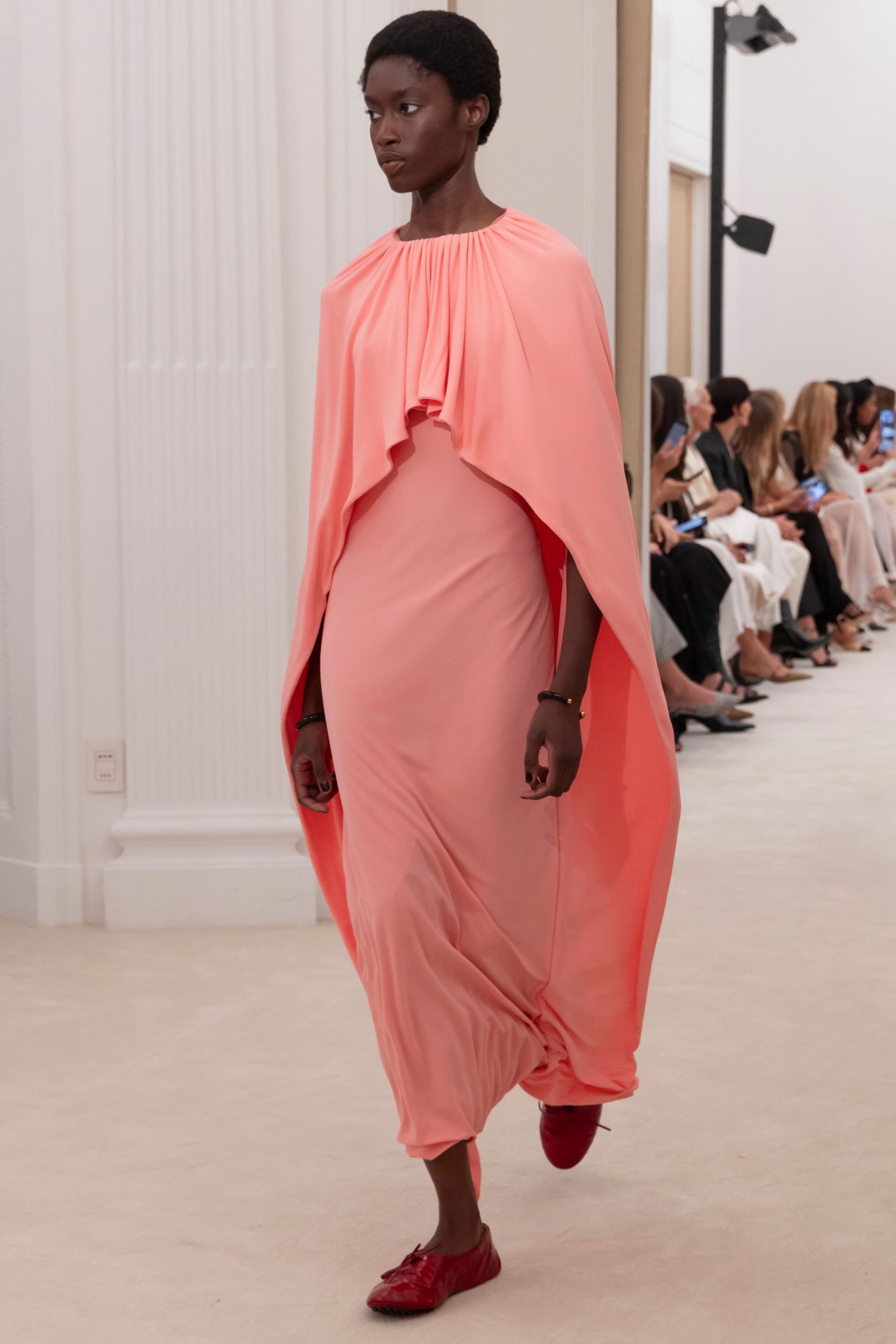 coral silk draped gown with red shoes