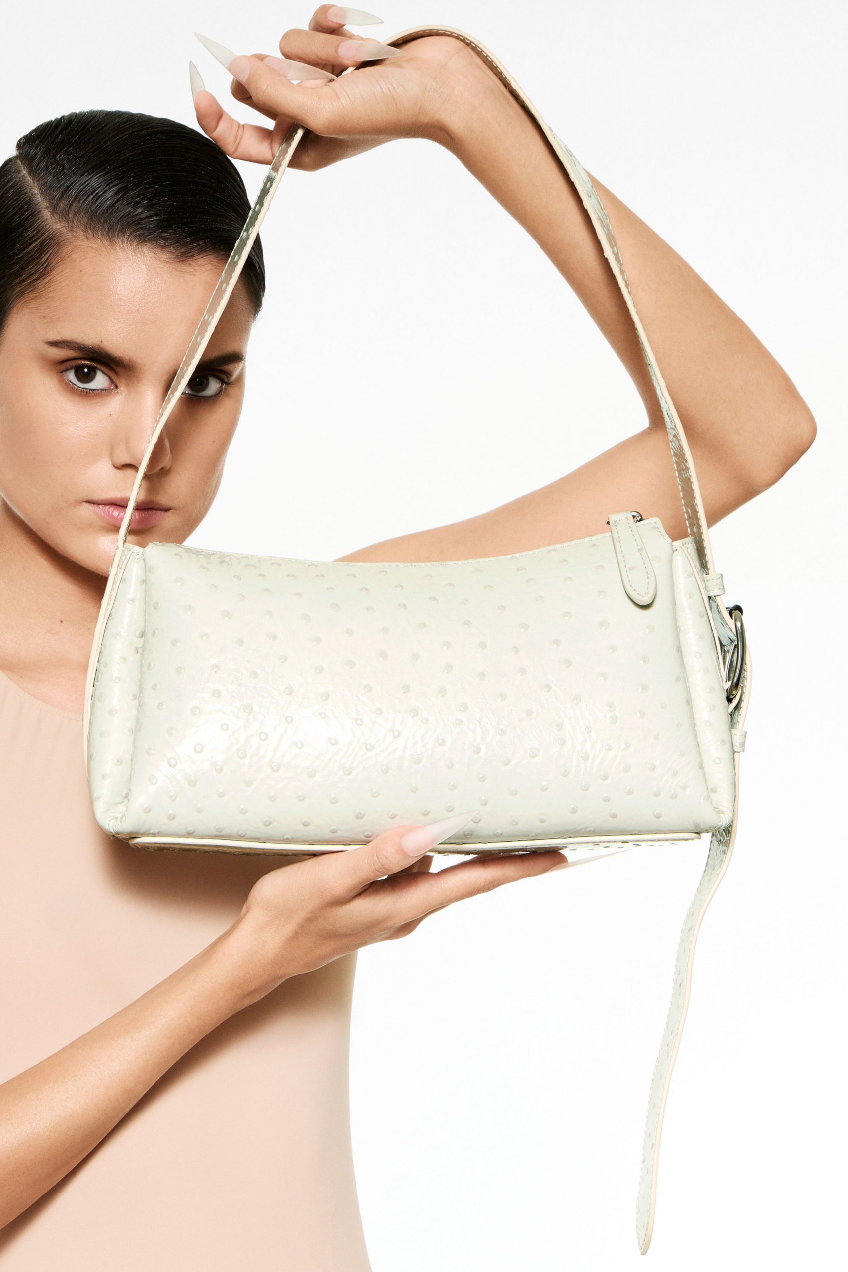 beige fitted sleeveless top and white bag