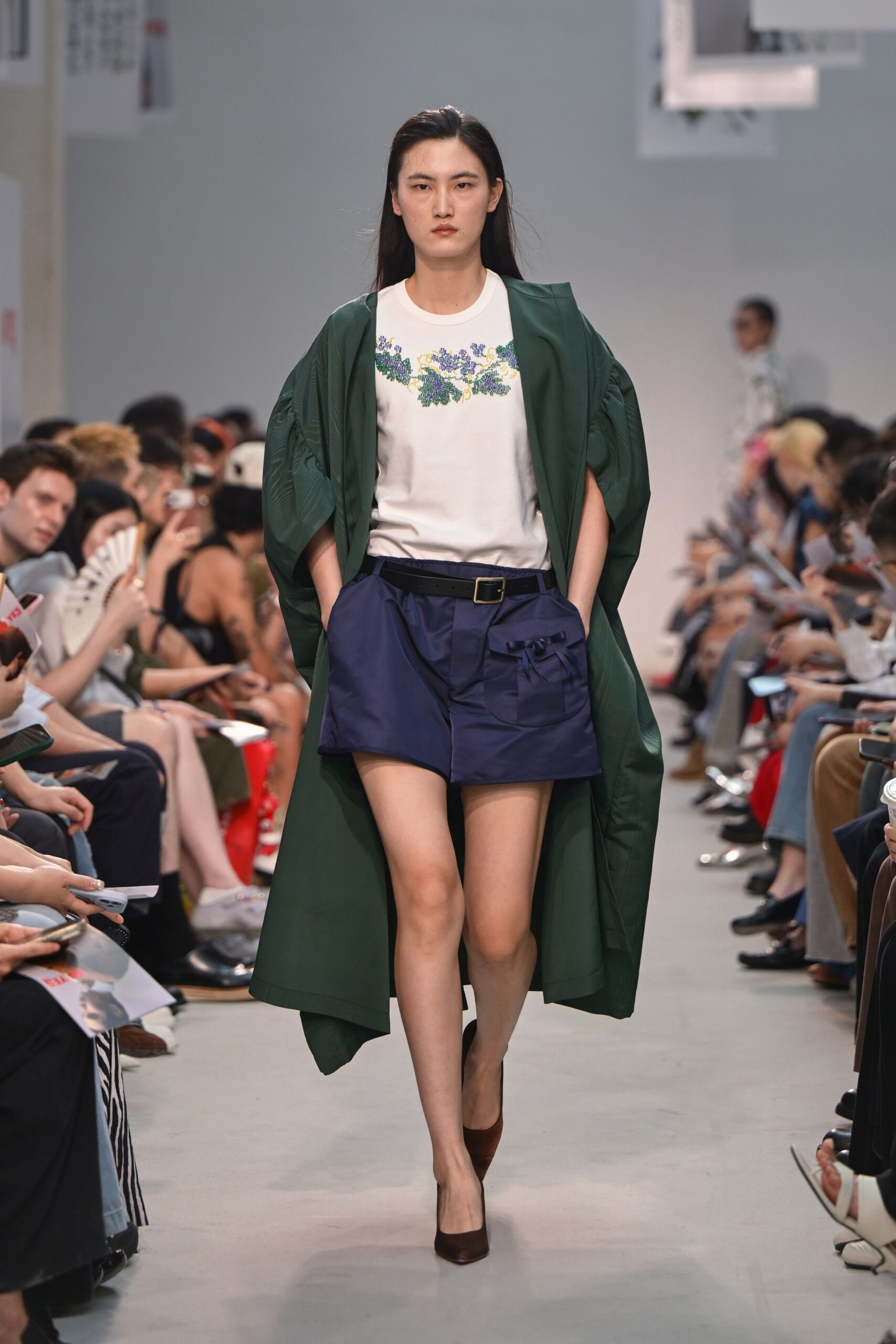 green coat white embroidered top blue shorts