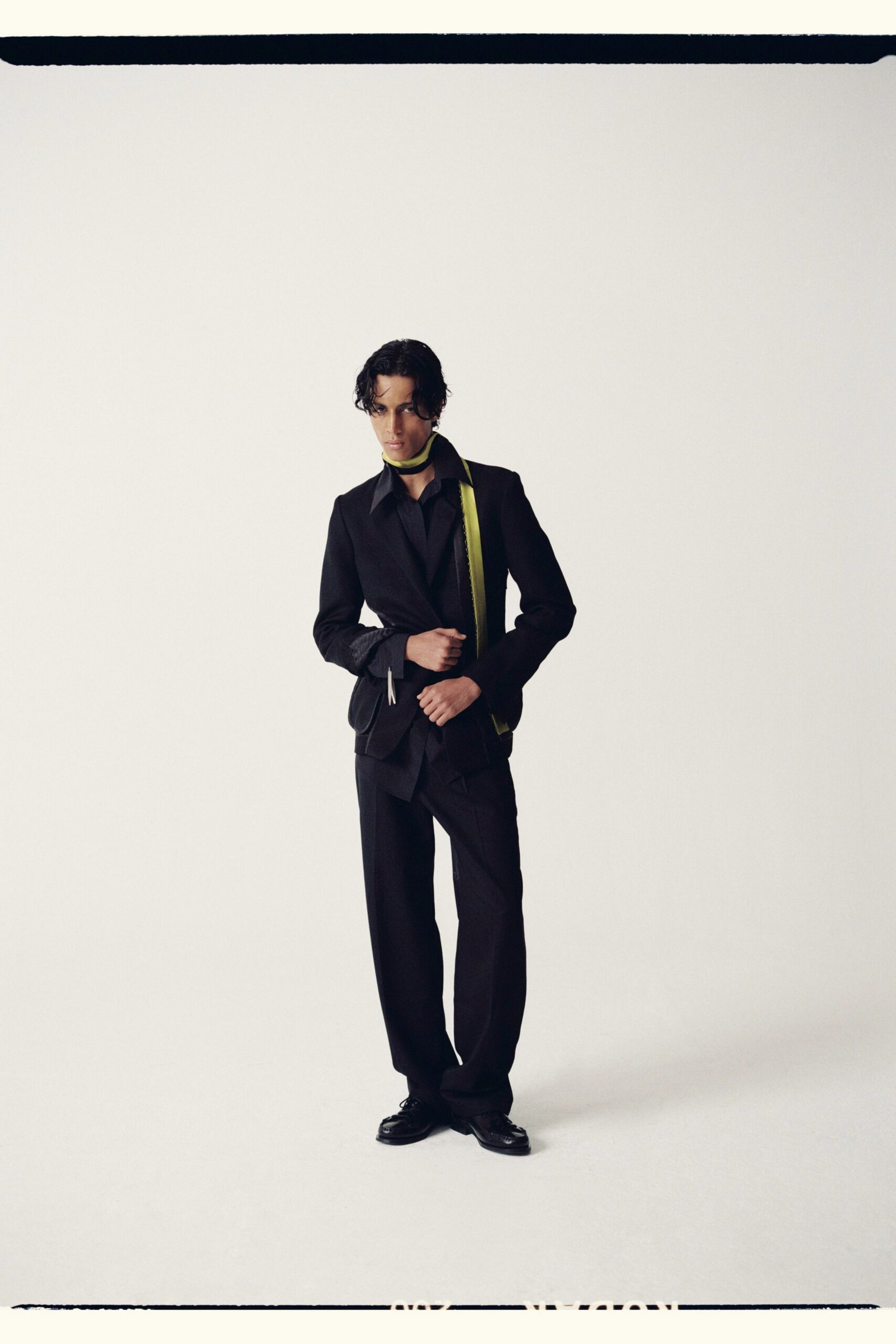 black tailored suit with green scarf