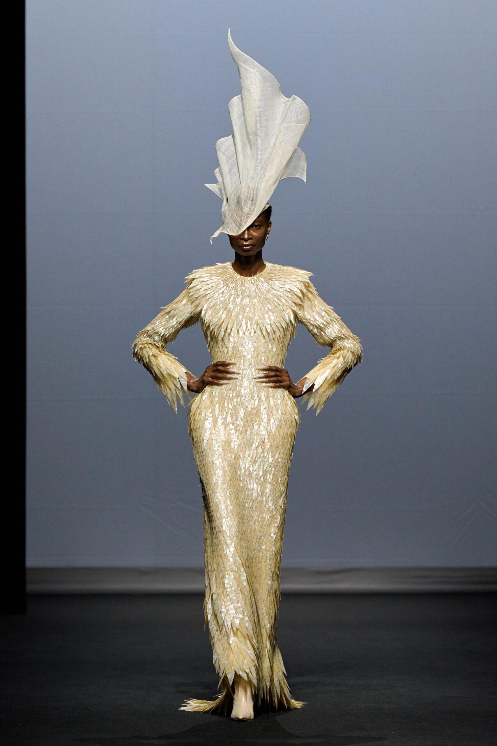 gold pleated gown with structured hat