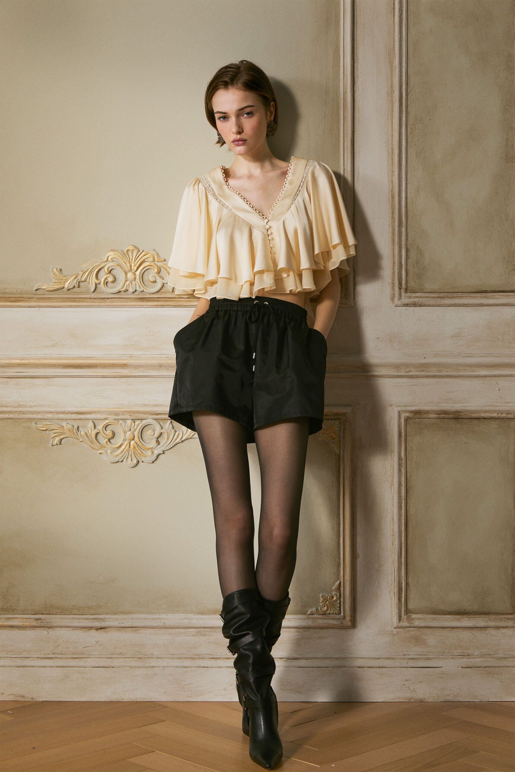 beige ruffled top with black shorts