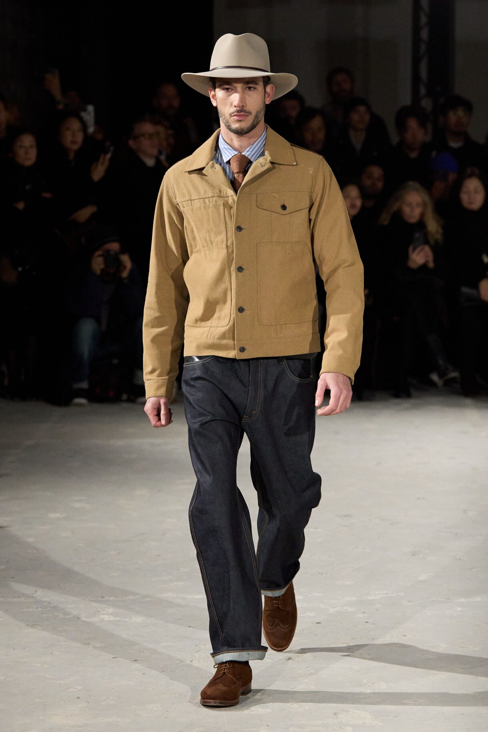 beige jacket blue pants brown shoes gray hat