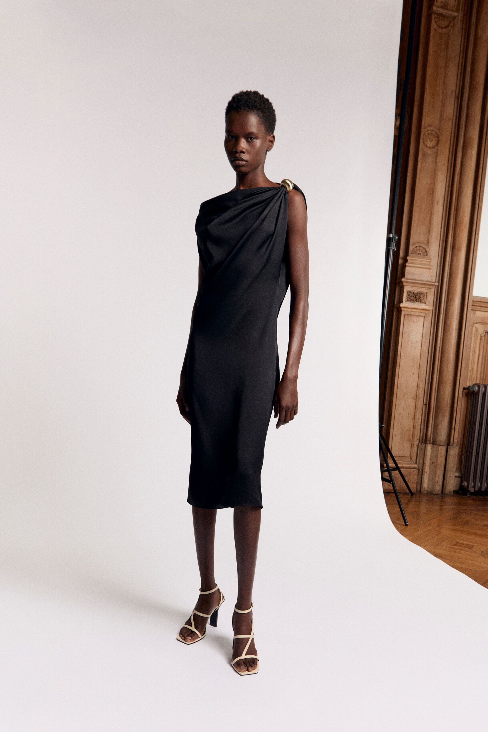 black silk draped midi dress with gold heels