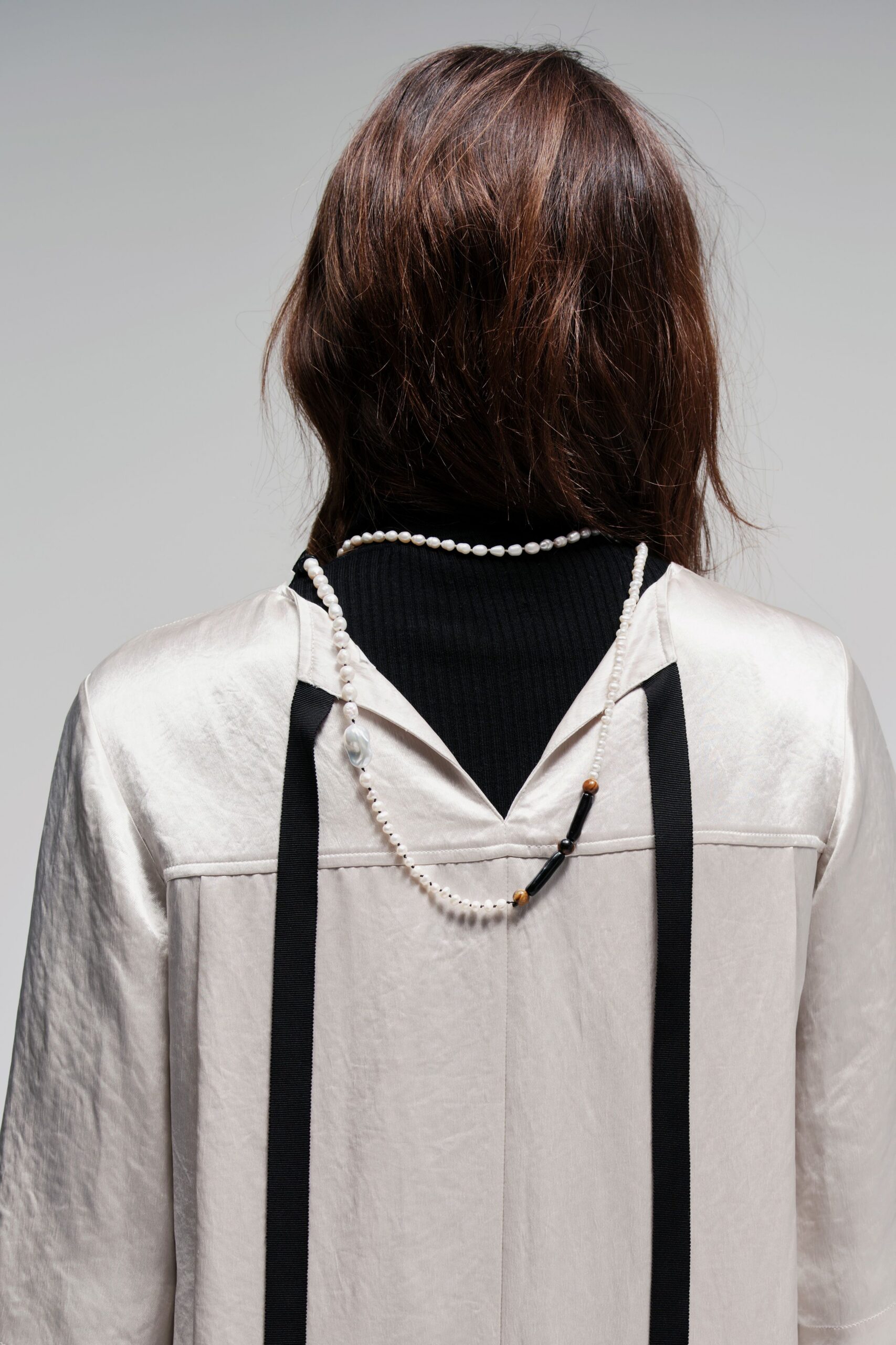 beige silk relaxed coat and black turtleneck top