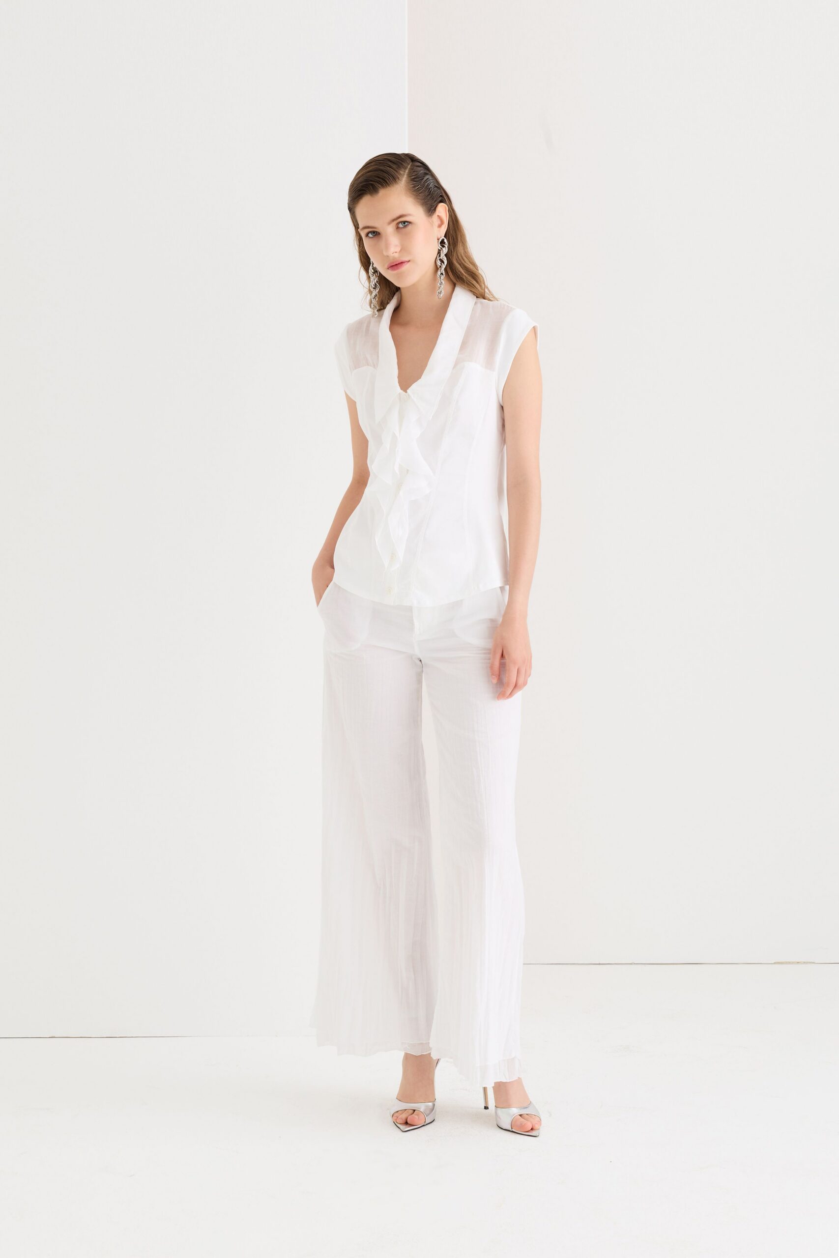 white ruffled top with pleated pants