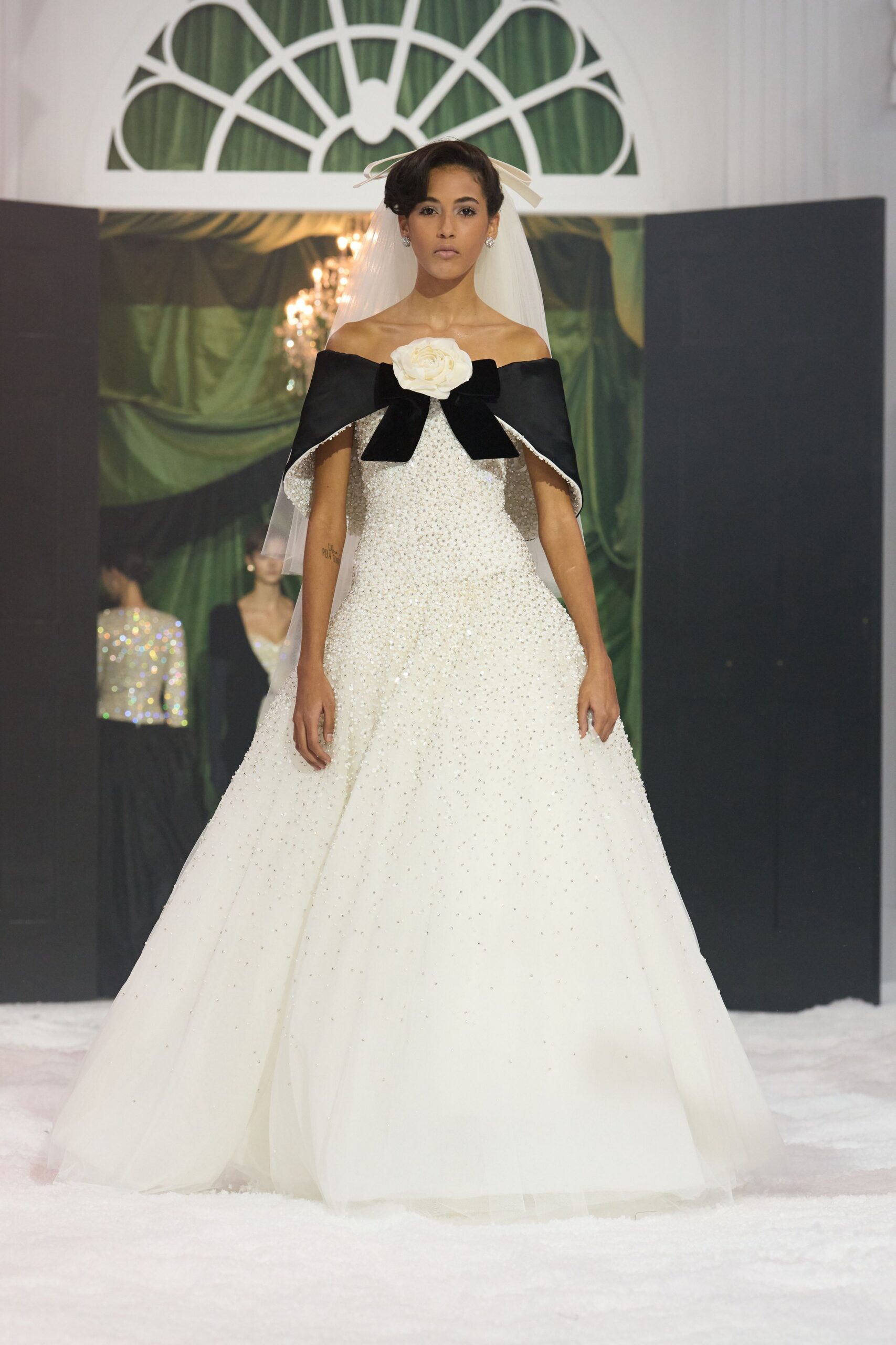 white beaded off-shoulder gown with black cape