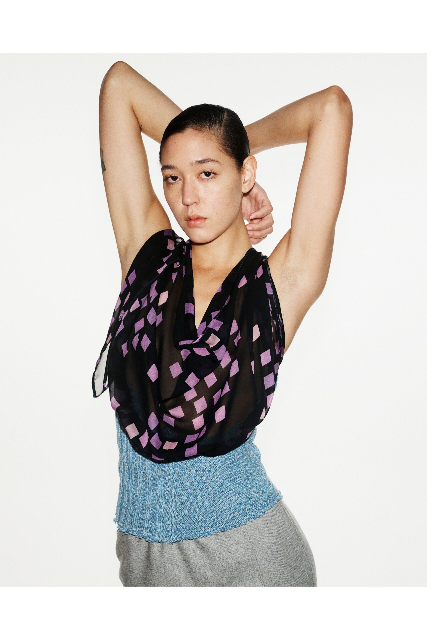 black and purple draped top with gray tailored pants