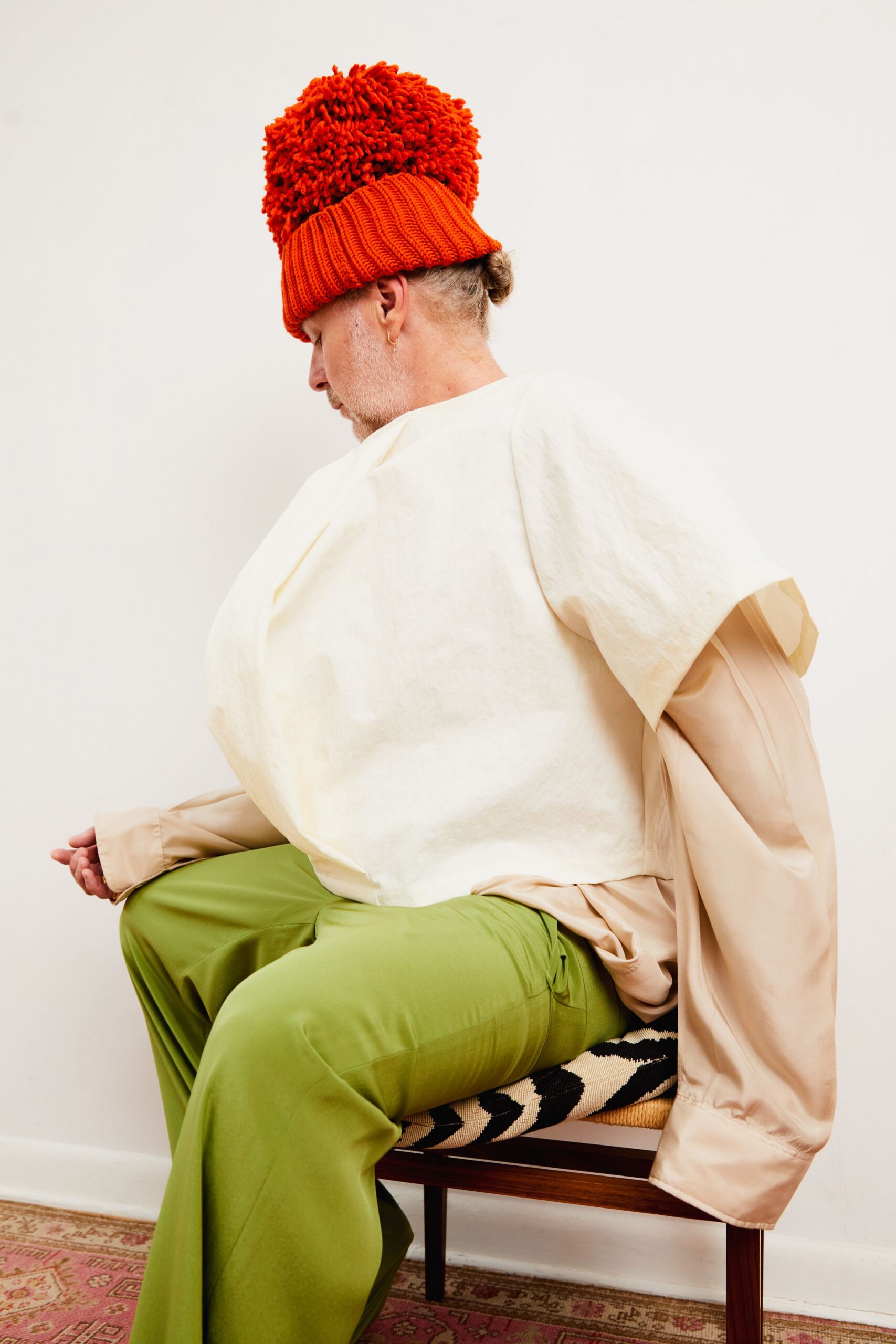 white relaxed top beige oversized jacket green relaxed pants orange hat
