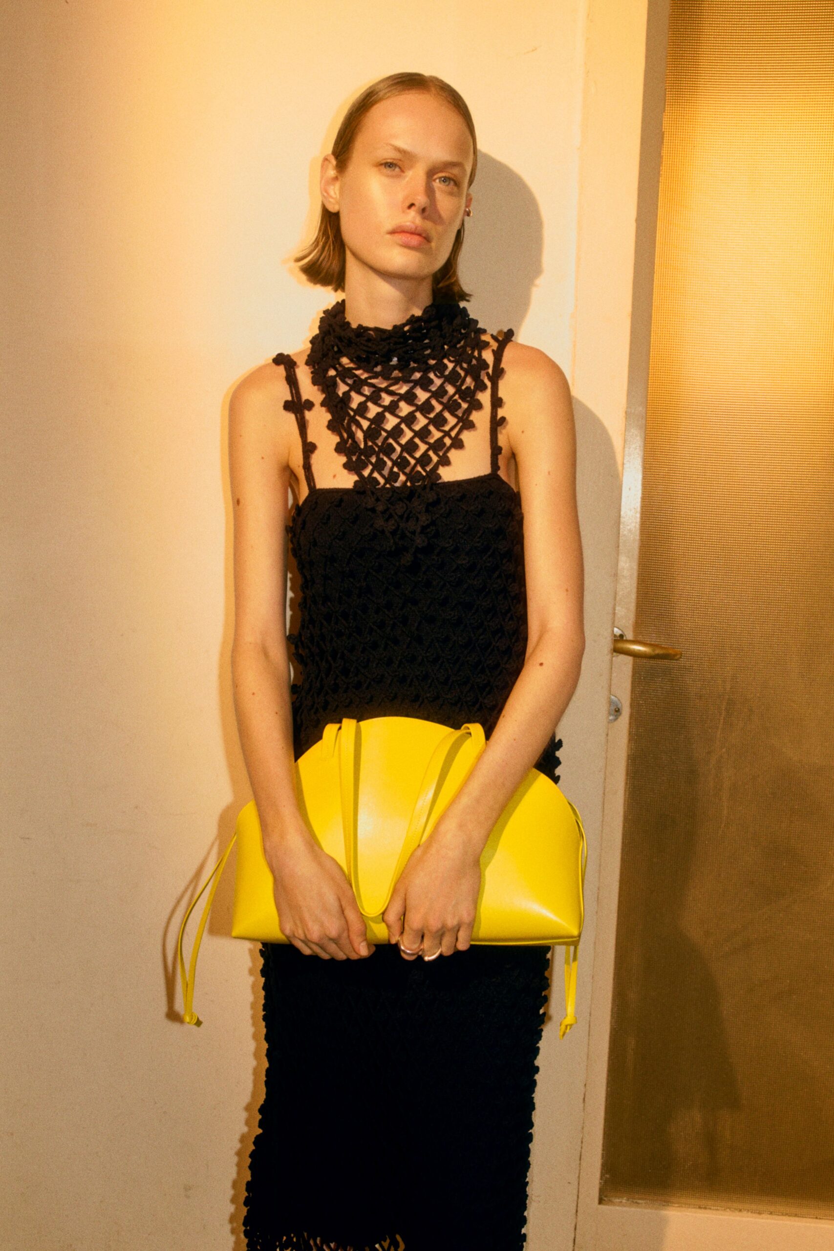 black fitted sleeveless dress with yellow bag