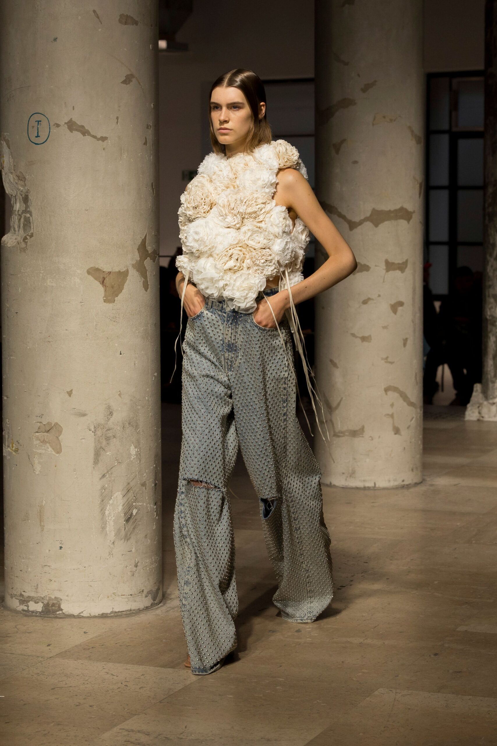 white fitted top with layered details and blue relaxed pants