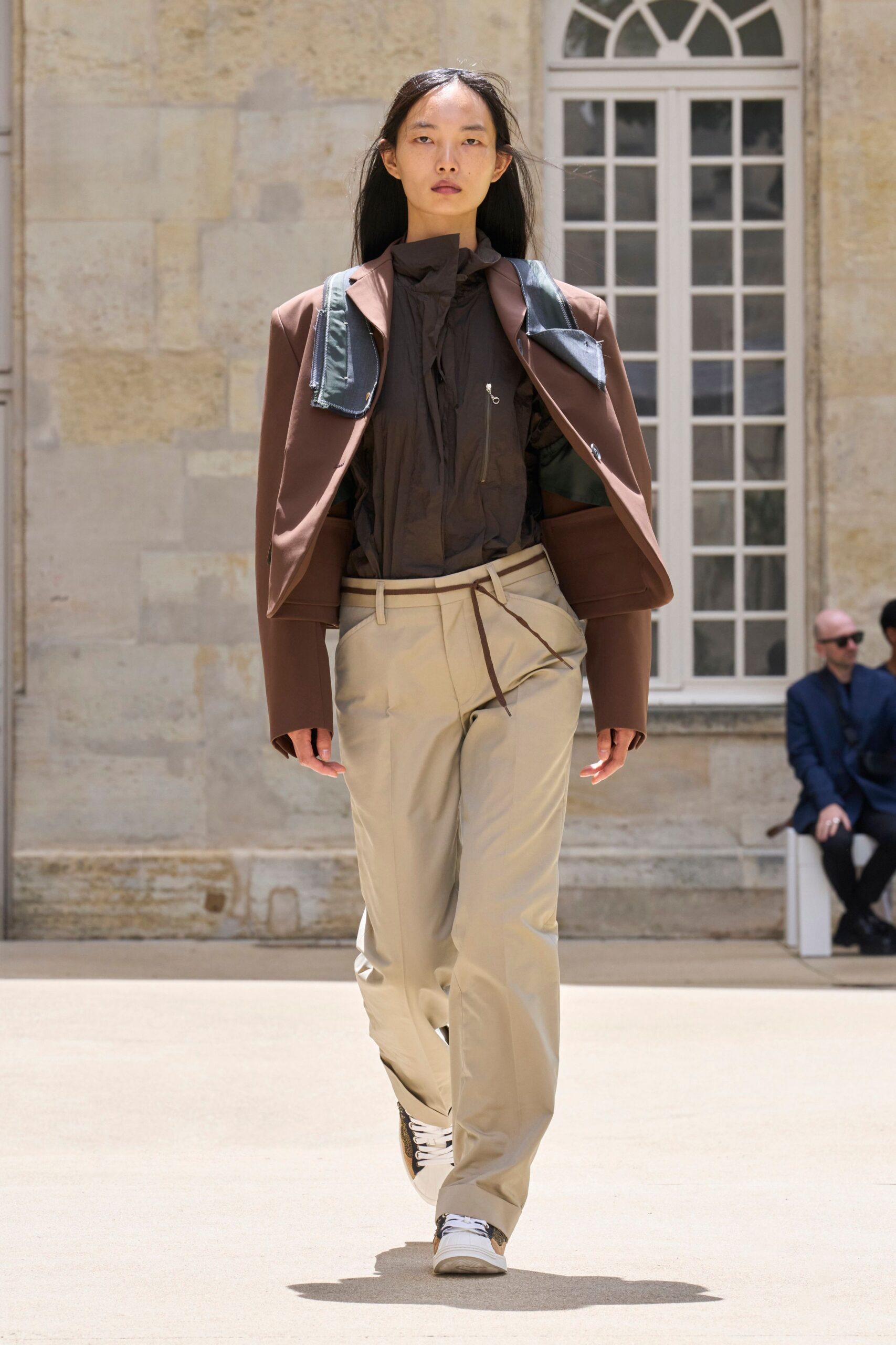 brown jacket black shirt beige pants white sneakers