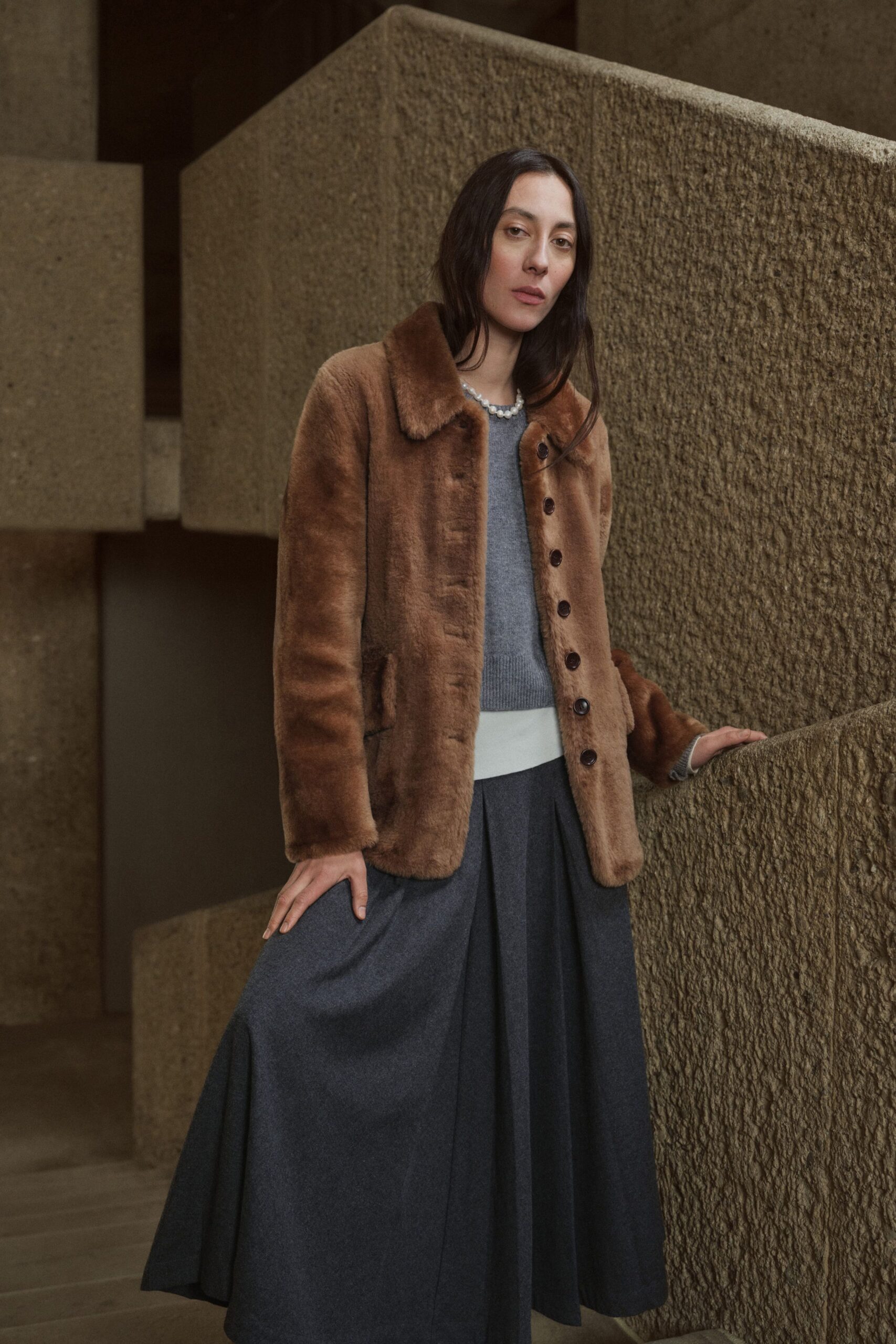 brown faux-fur coat with gray sweater and black pleated skirt