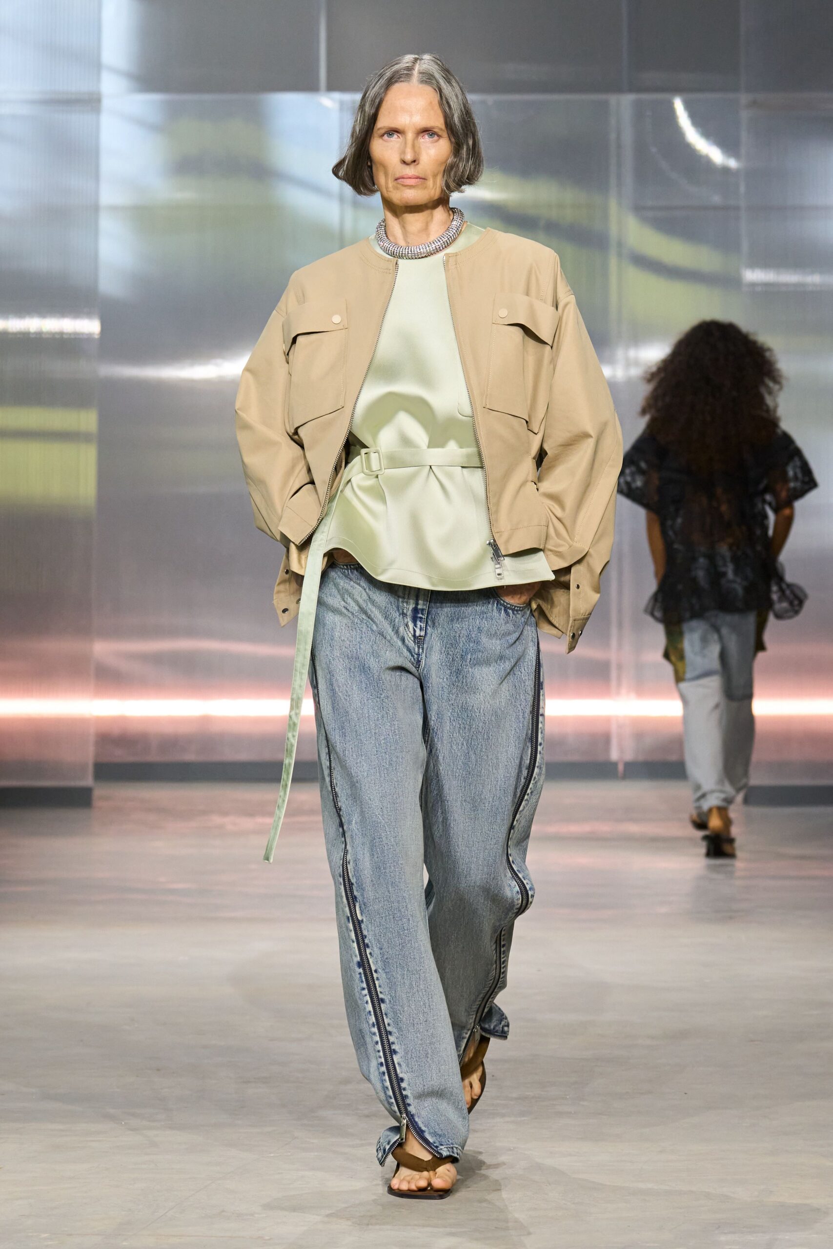 beige jacket green top blue jeans