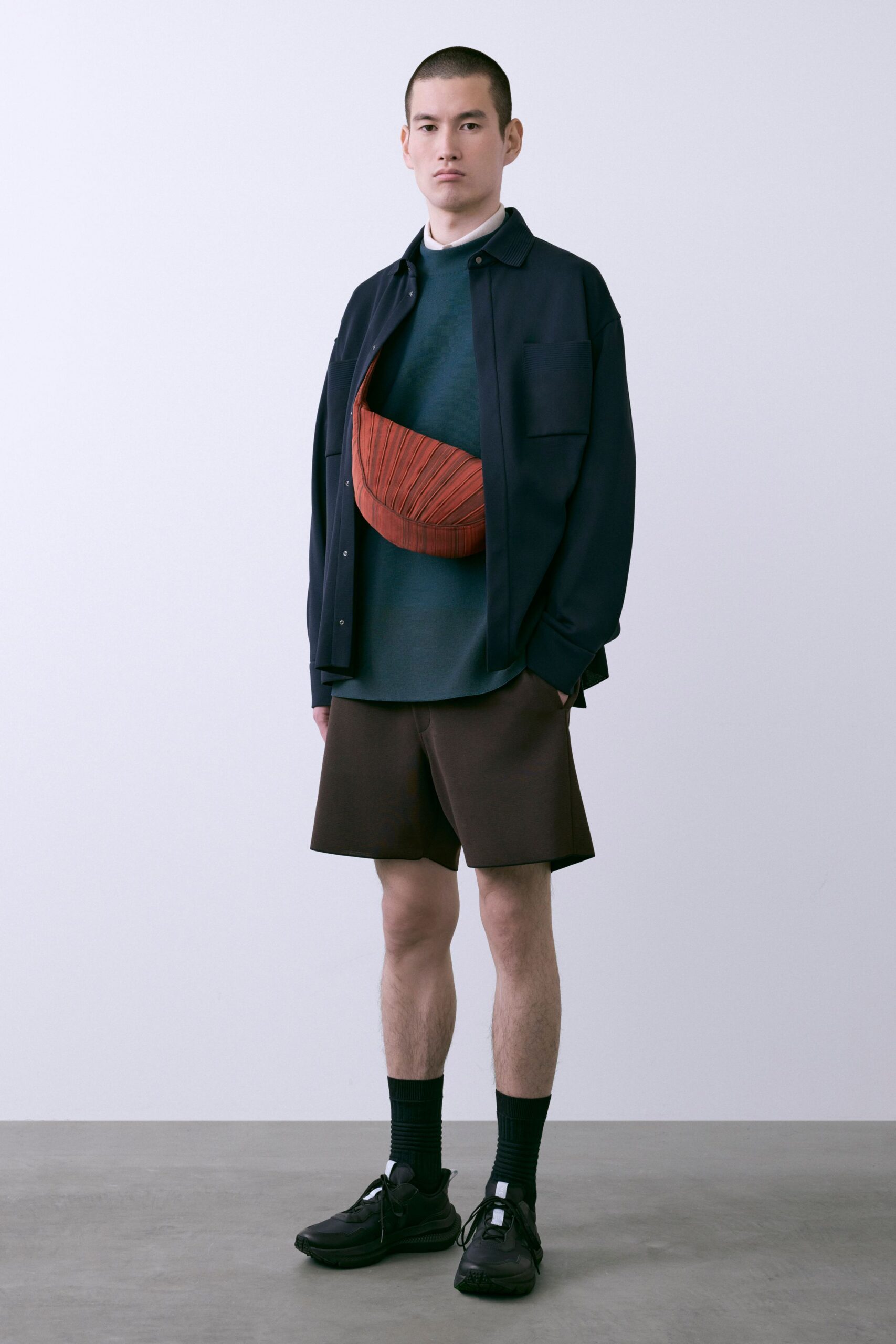black shirt blue turtleneck brown shorts red bag